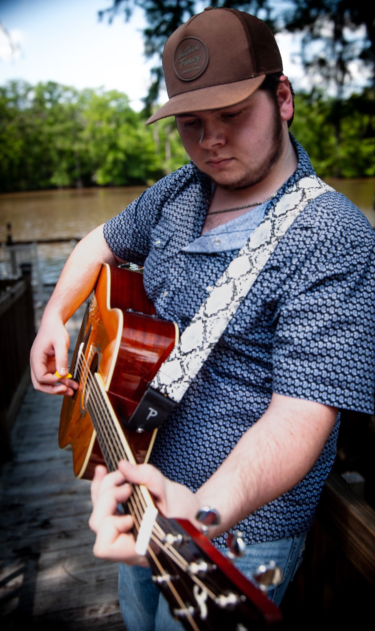 Close-up shots of guitarist playing orange acoustic guitar on wooden deck.