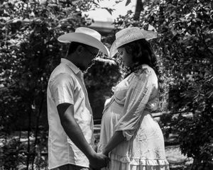 Vintage black and white photograph showing a couple dancing together outdoors in a garden setting.