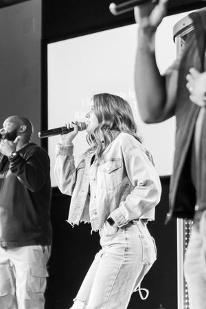 People in white outfits performing on stage during a church service.