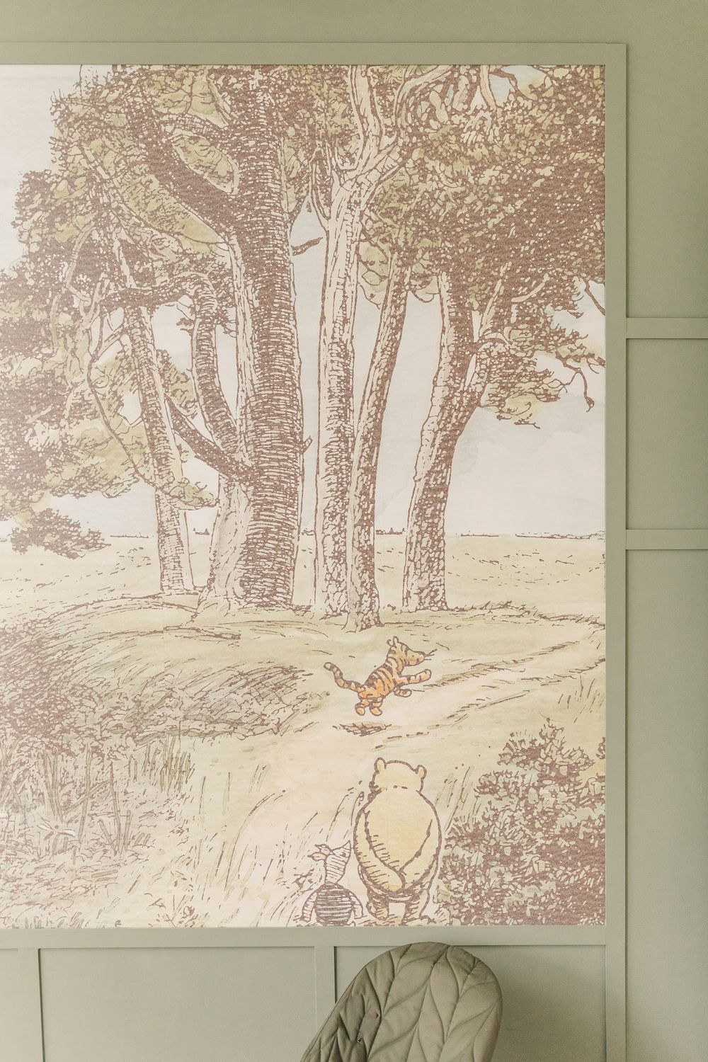 Nursery wall with Winnie-the-pooh wallpaper and green trim and walls.