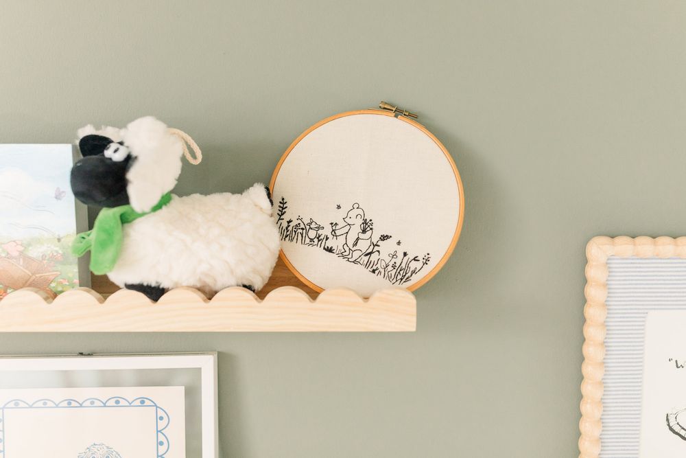 Shelf in a nursery with a Winnie-the-pooh cross stitch