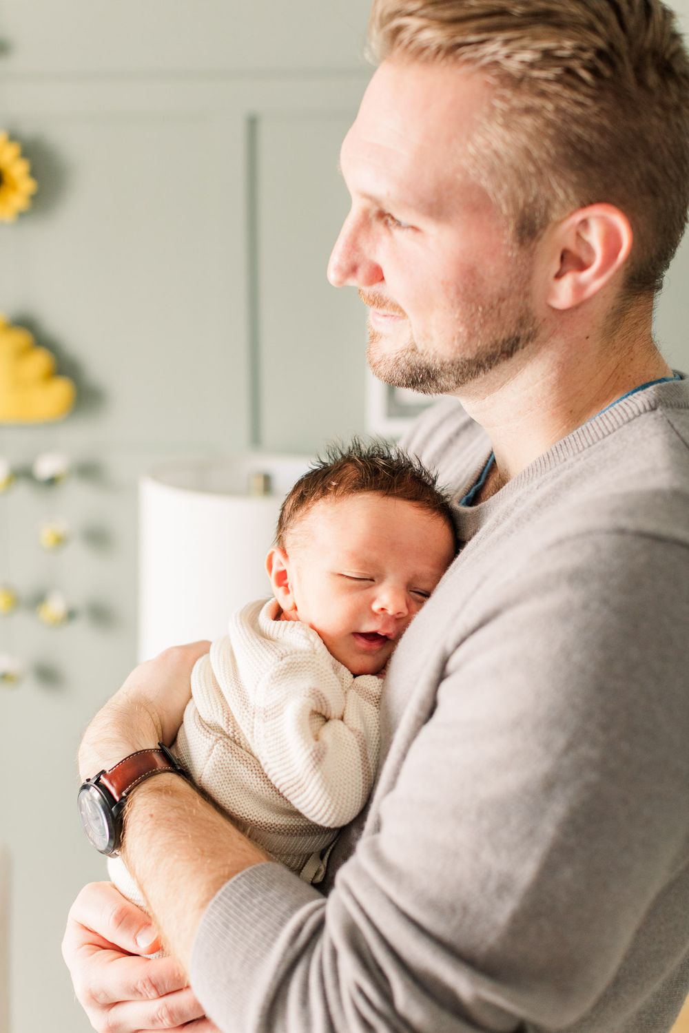 Dad holding sleeping baby and looking out the window