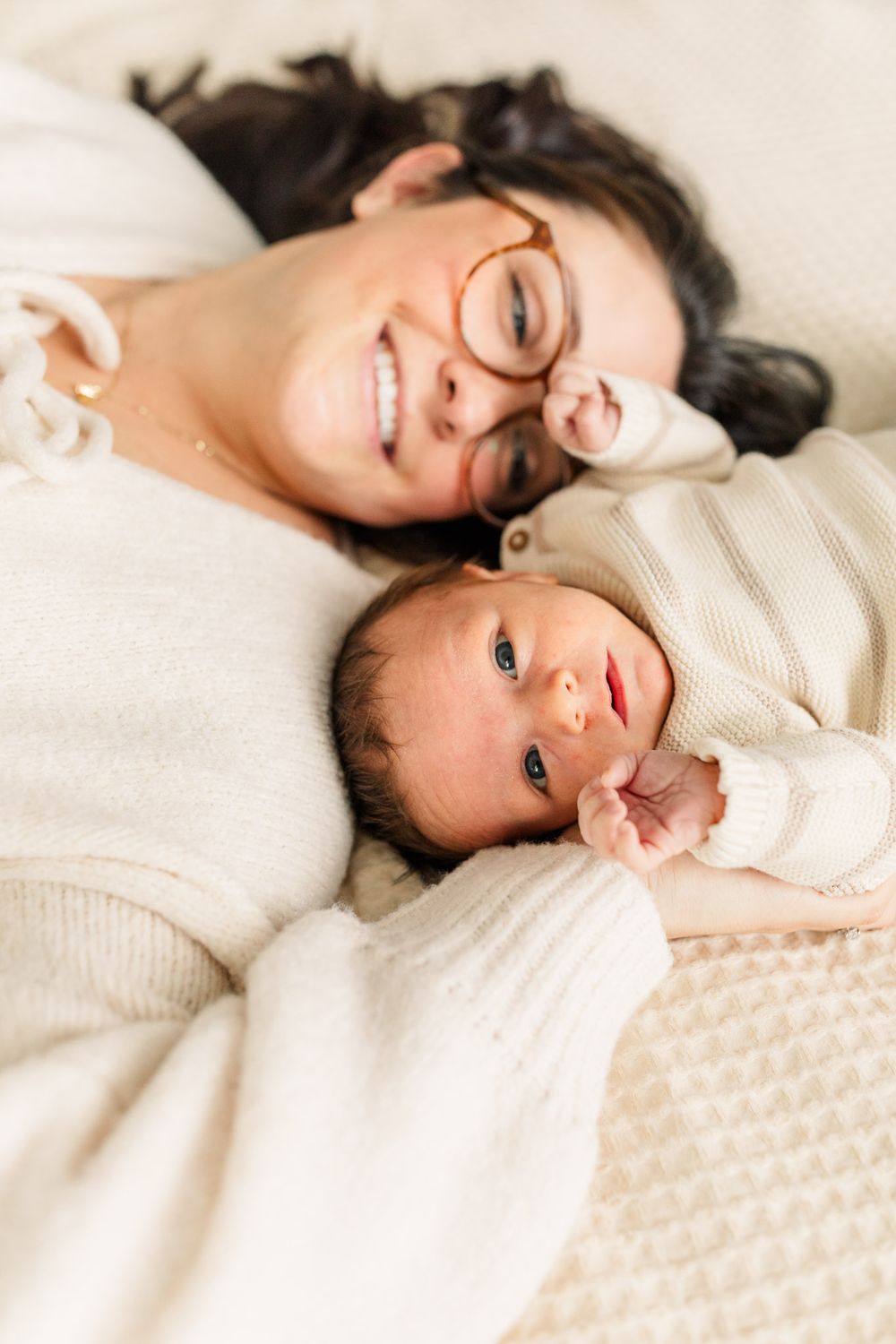 Mom snuggling newborn baby on bed