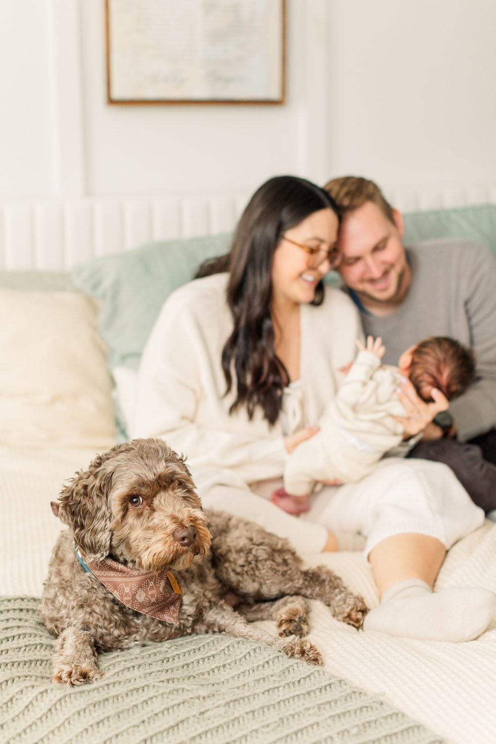 Lifestyle newborn photography at home in Richmond VA with dog and parents on bed with baby