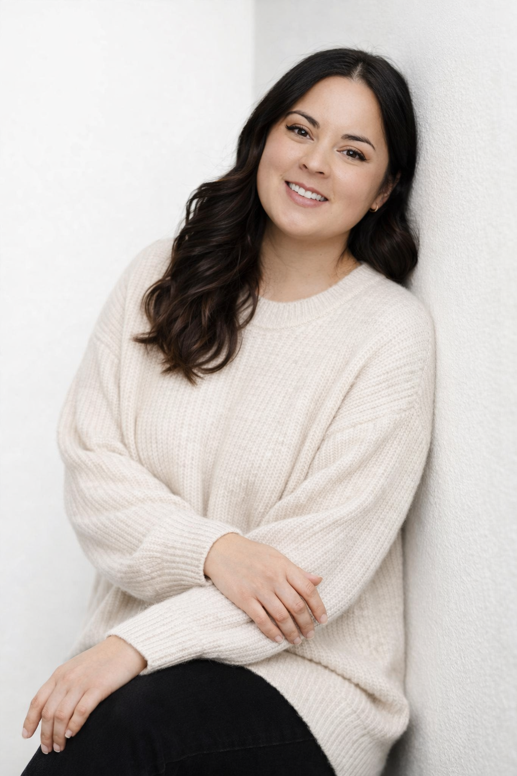 Person wearing a cozy cream sweater poses against white background in casual portrait series.