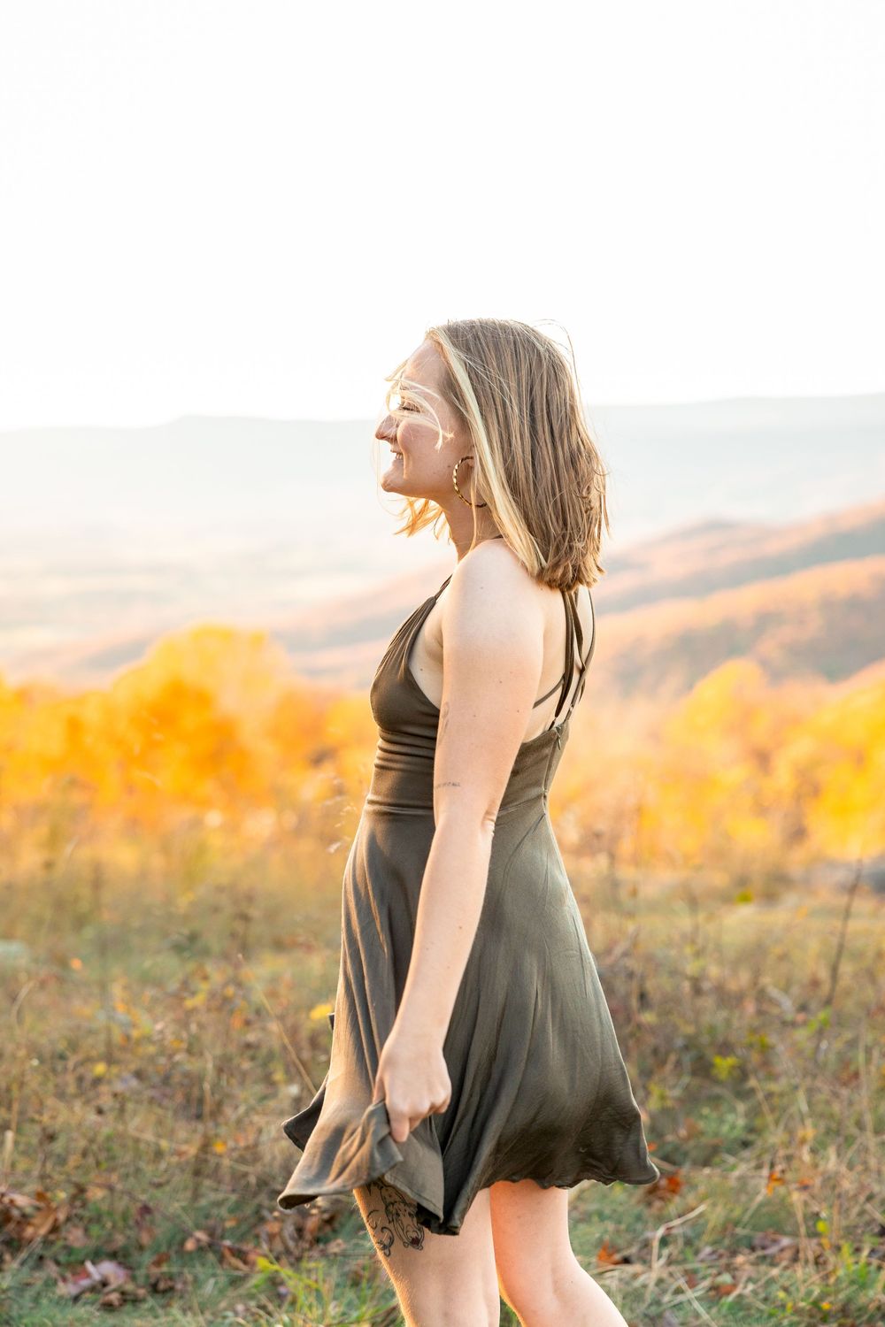 A person in a black dress dances gracefully in a golden autumn field at sunset.
