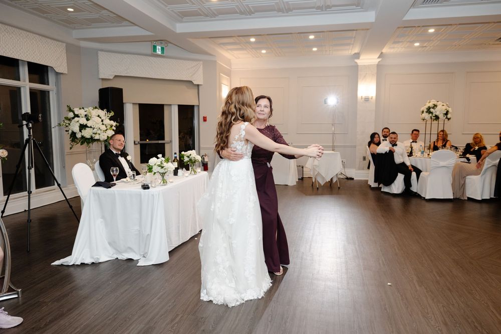 An elegant white wedding reception venue with coffered ceilings and hardwood floors decorated for a celebration.