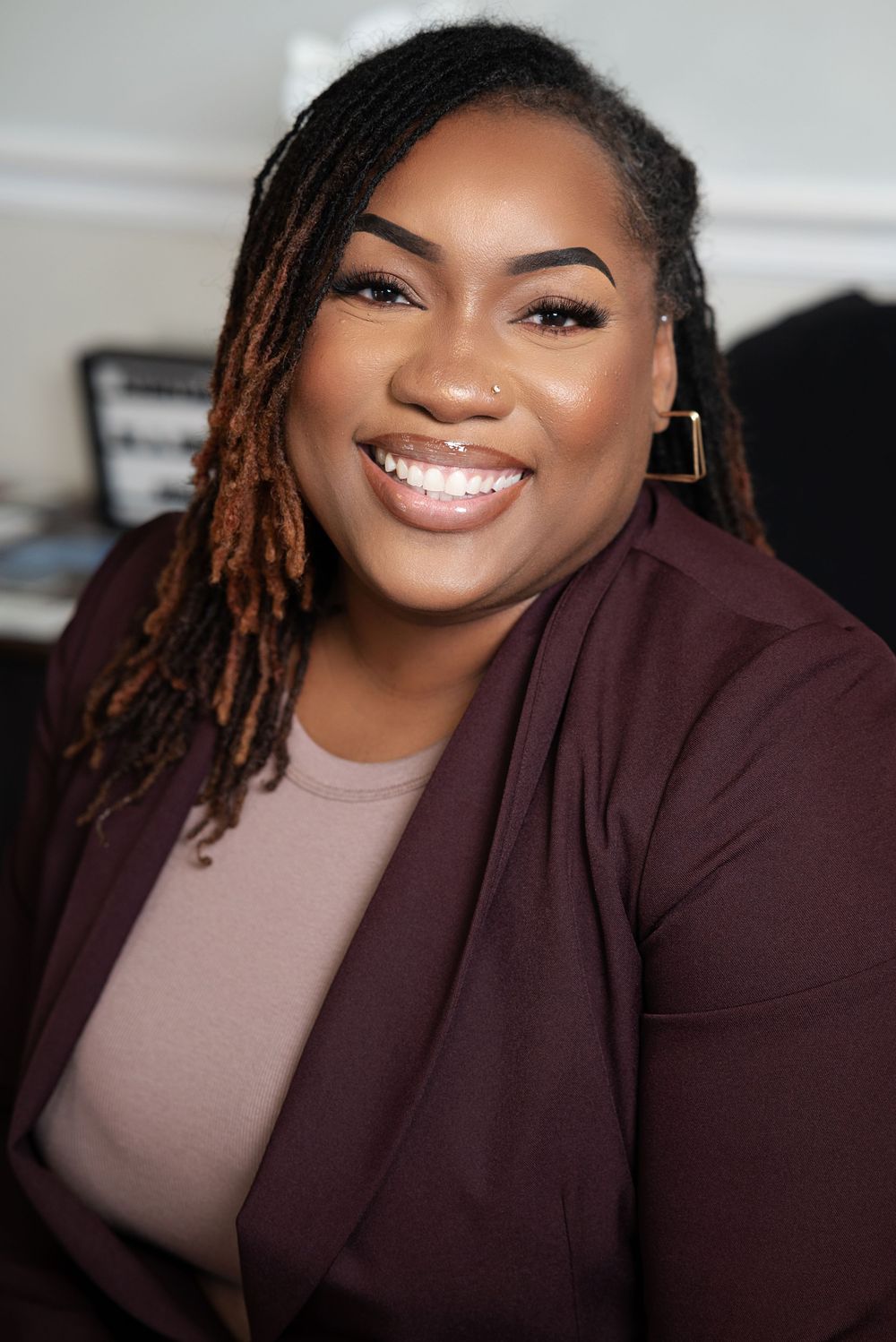 Professional headshot series showing bright smile and locs hairstyle against dark background.