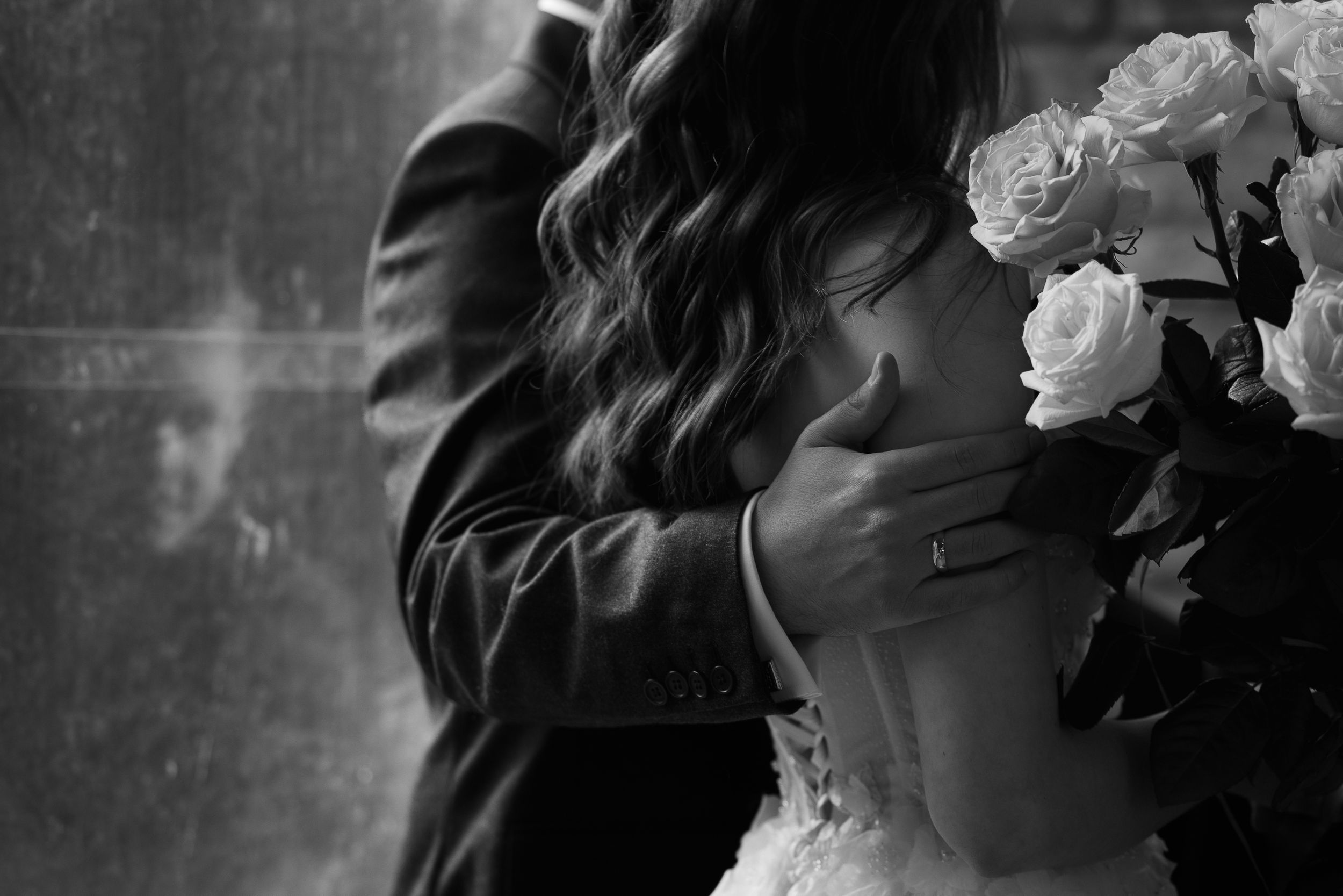 Black and white wedding photos show intimate moments between a couple with flowers and romantic lighting.