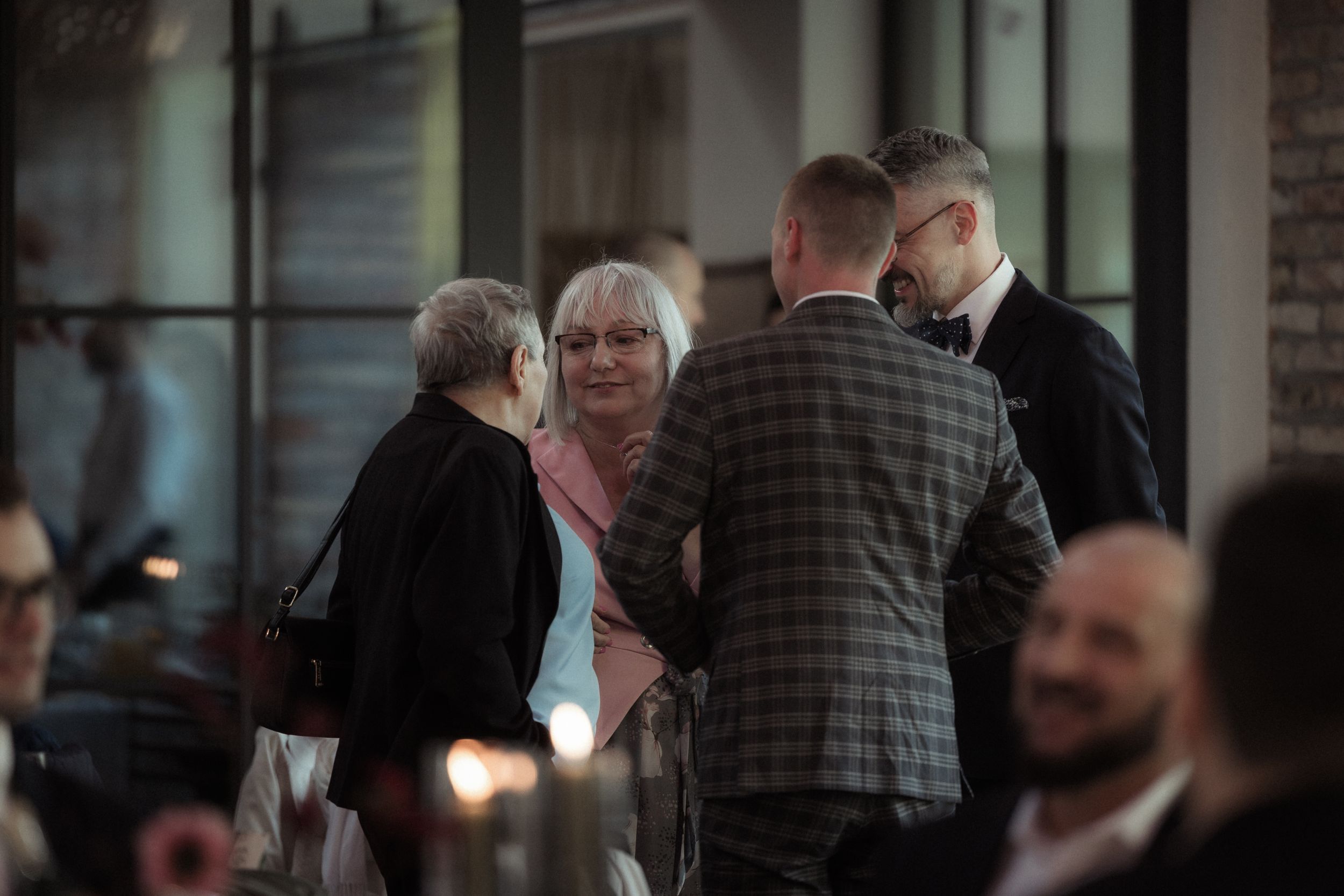 Guests mingle and socialize at an elegant indoor event with warm lighting and formal attire.