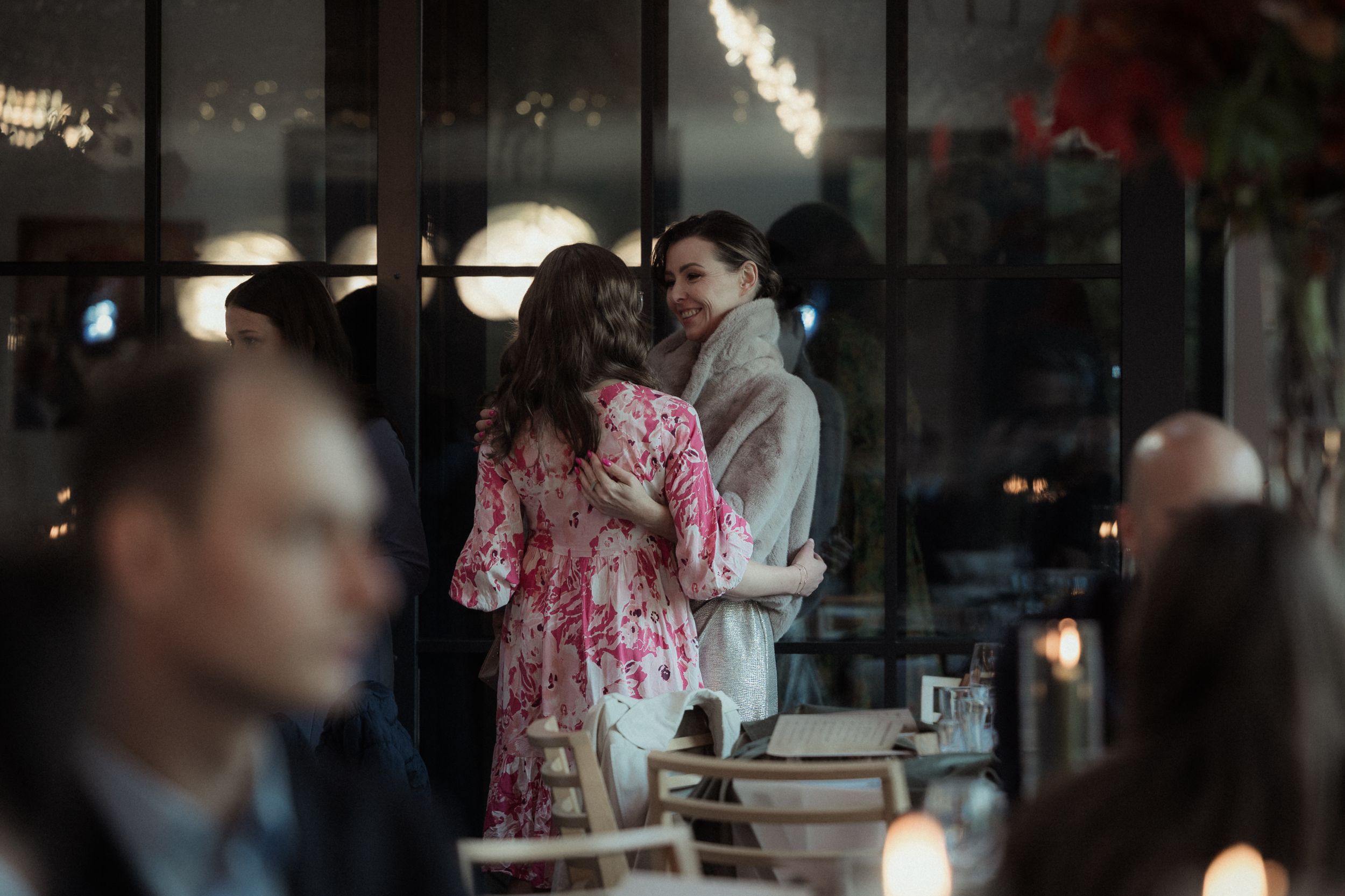 Diners enjoy a meal in a dimly lit restaurant with modern decor and ambient lighting.