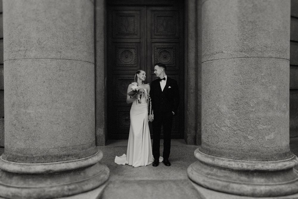 Architectural wedding portrait featuring classical columns and wooden doors.