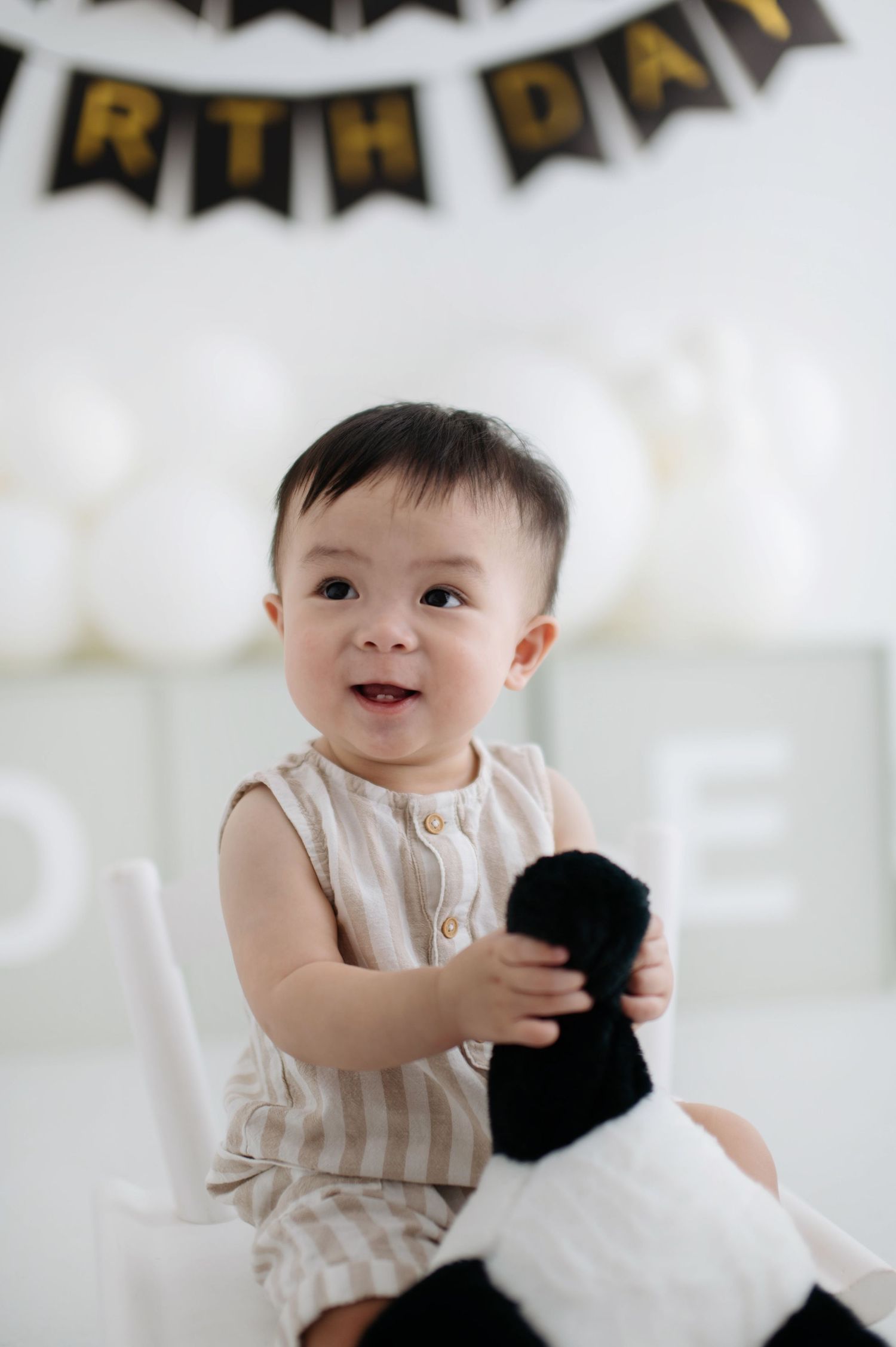 A joyful birthday celebration scene with black and gold decorations and a plush toy companion.