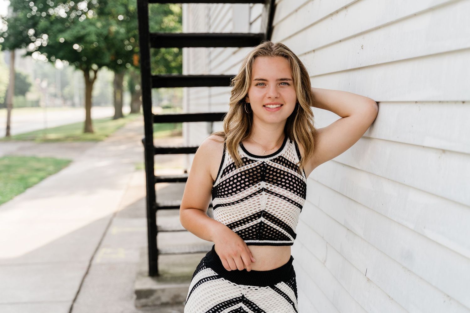 Perrysburg senior photos of Eliza in black and white fitted dress near Maumee River downtown streets