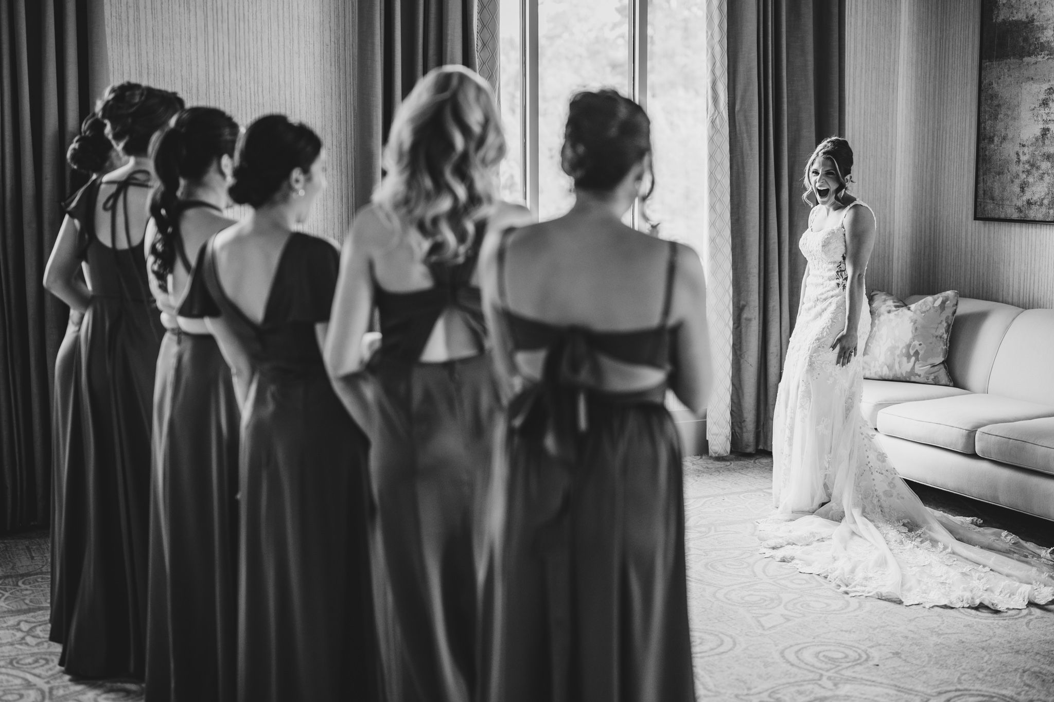 Bridesmaids in dark dresses create dramatic silhouettes while getting ready for the wedding.