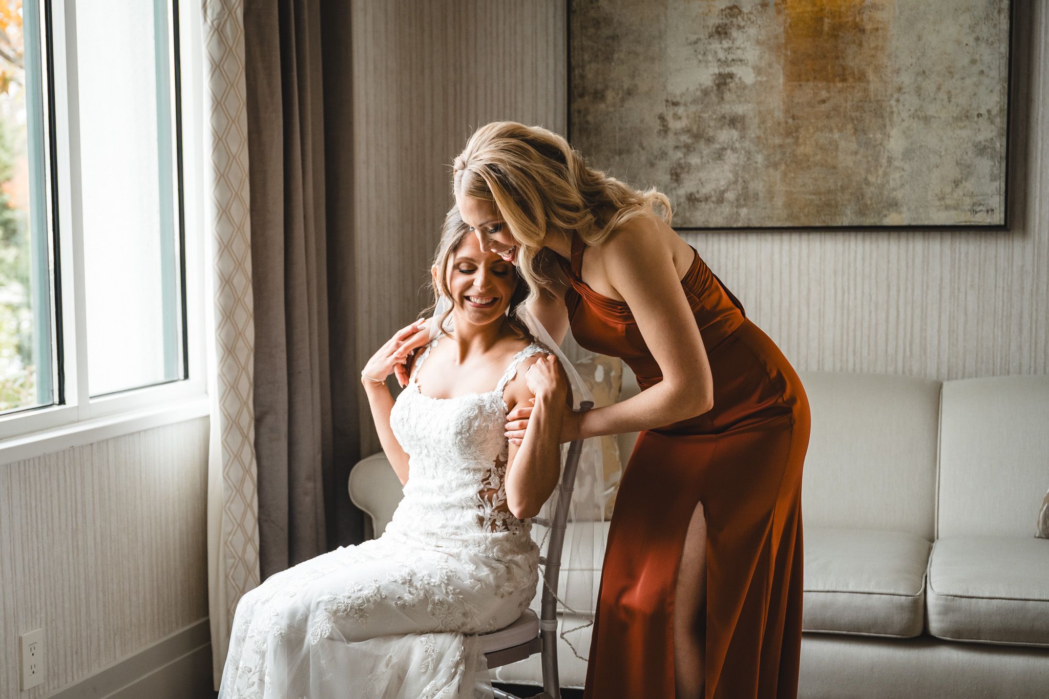 Emotional wedding preparation moment captured in room with exposed brick wall and natural light.