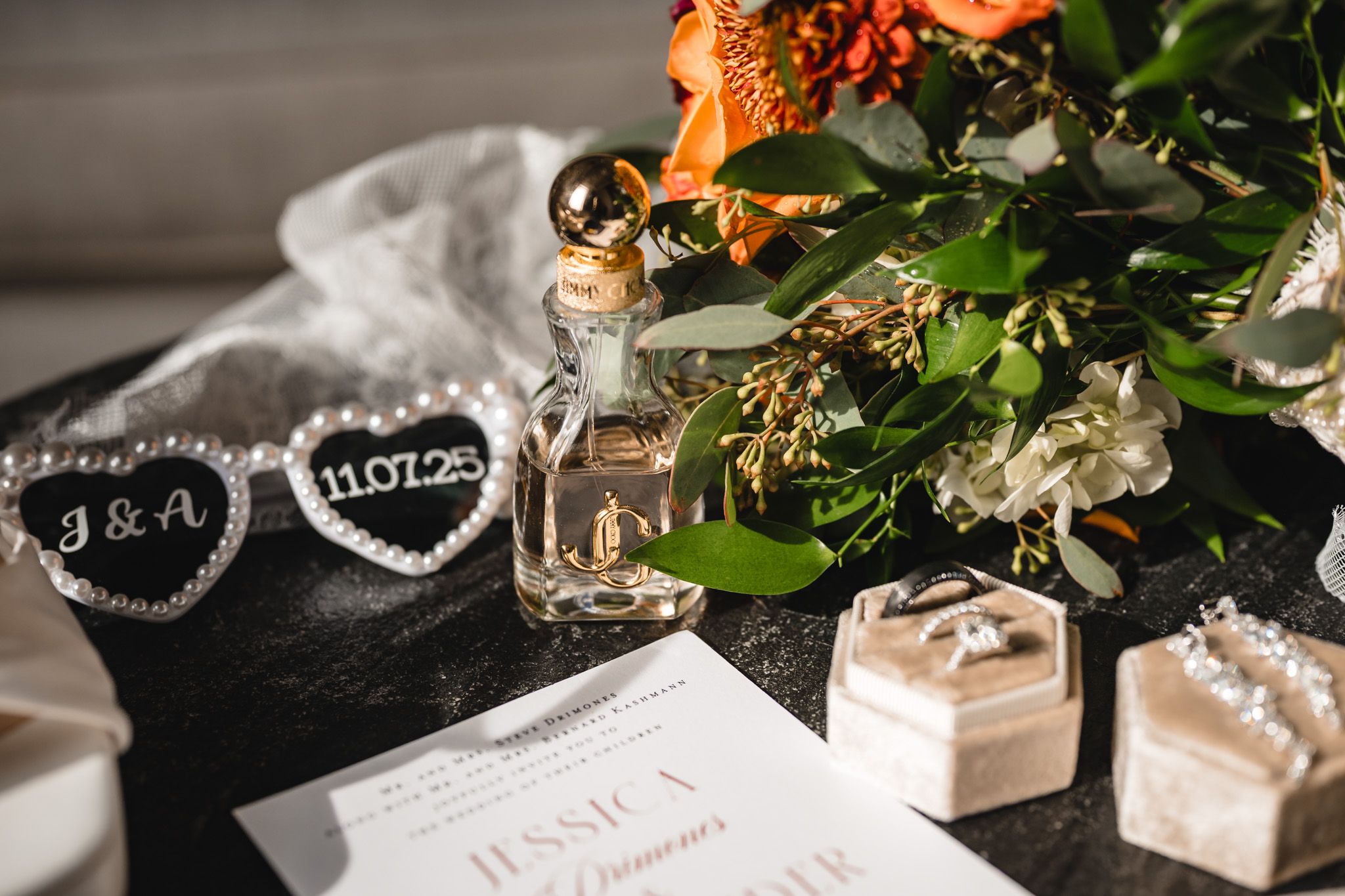 Elegant wedding stationery and decorative elements arranged with orange and green florals.