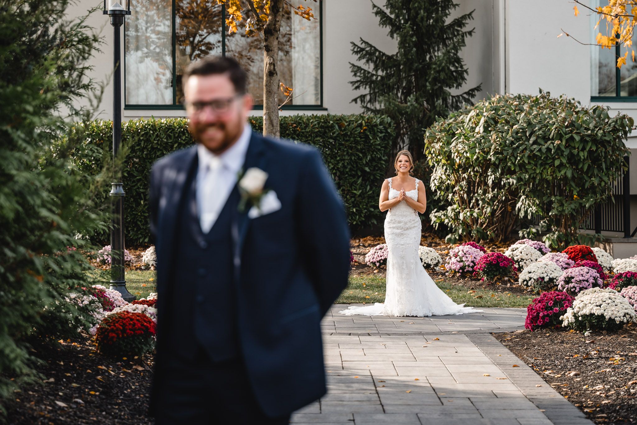 Outdoor wedding venue with evergreen trees and red flowers along stone pathway.