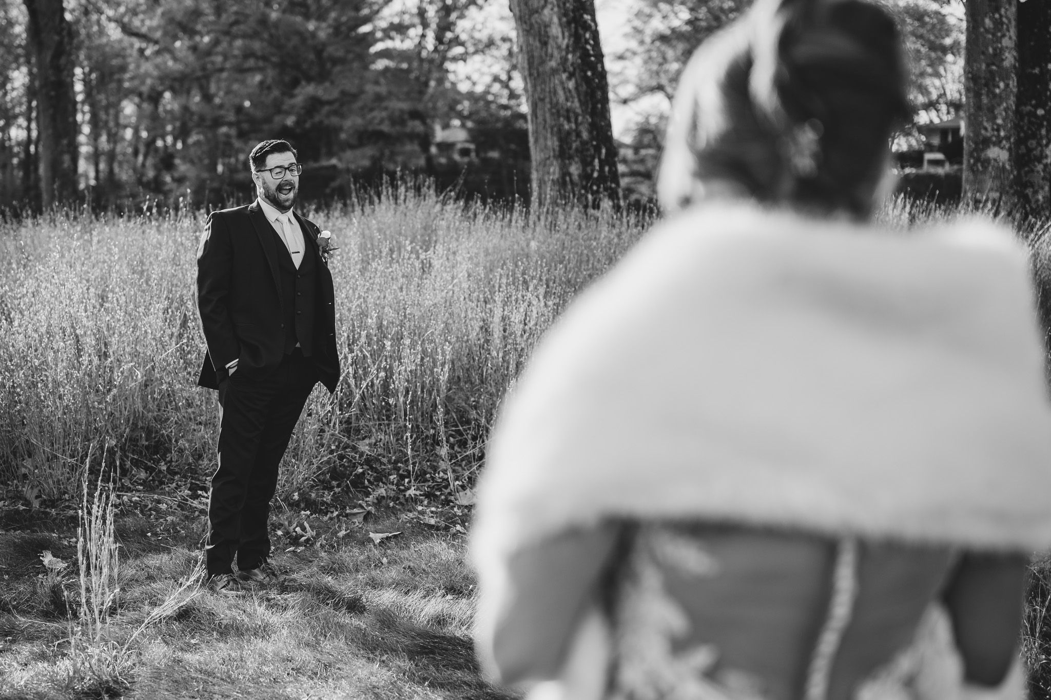 Wedding couple shares candid moment in rustic outdoor setting with natural light.