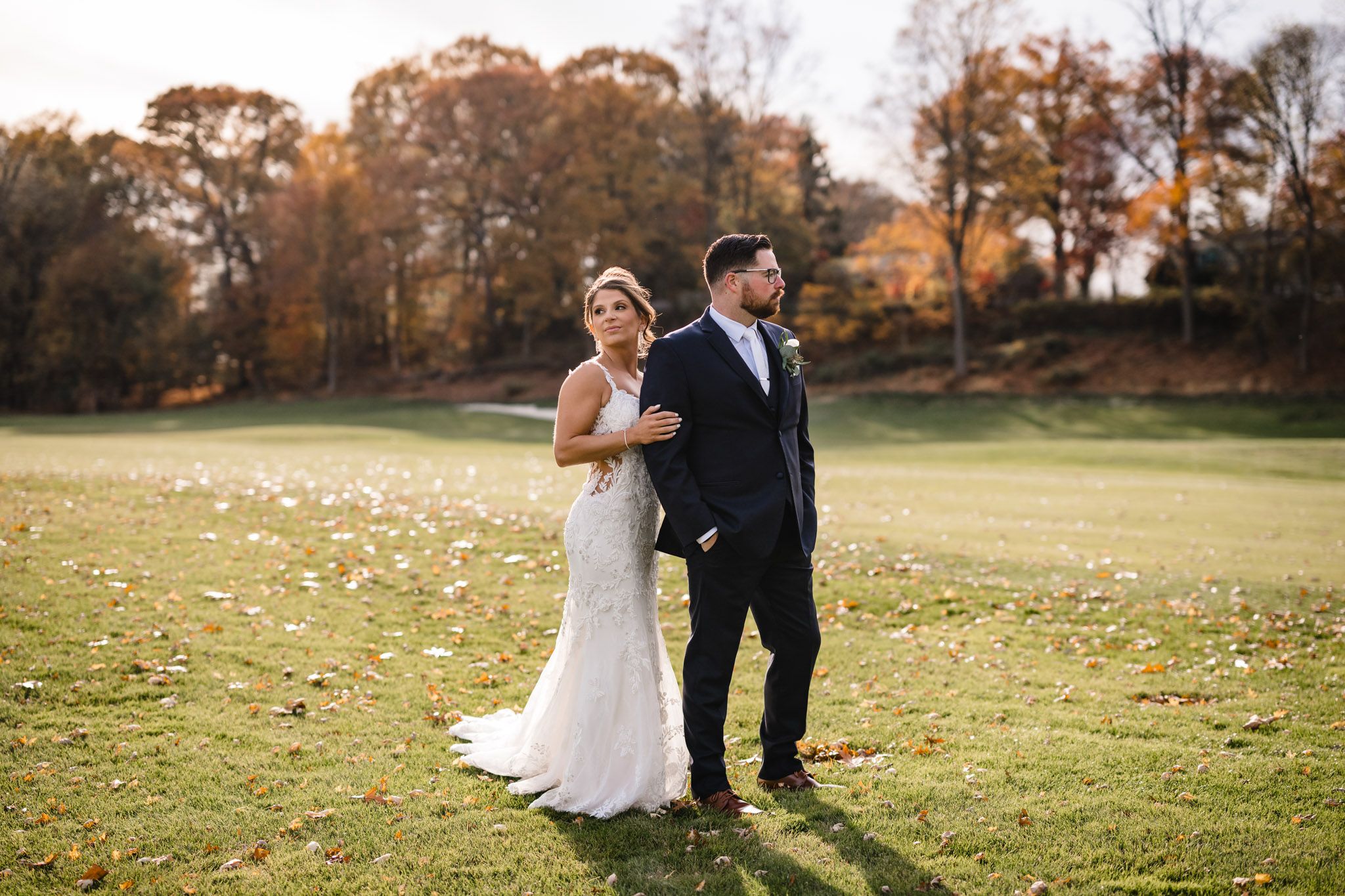 Newlyweds stroll together across rolling green hills of golf course.
