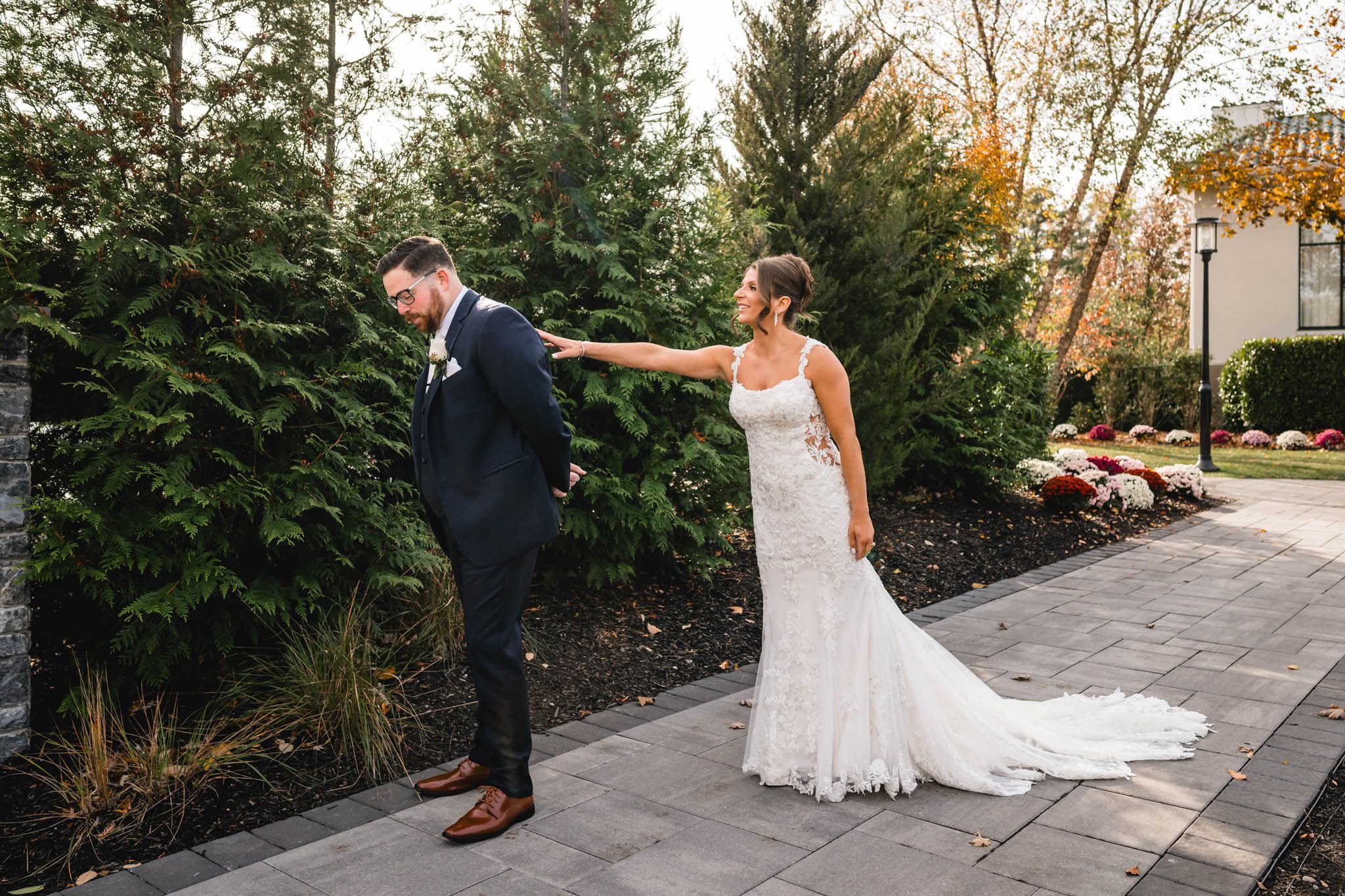 Romantic first look moment between couple on stone pathway surrounded by autumn foliage.