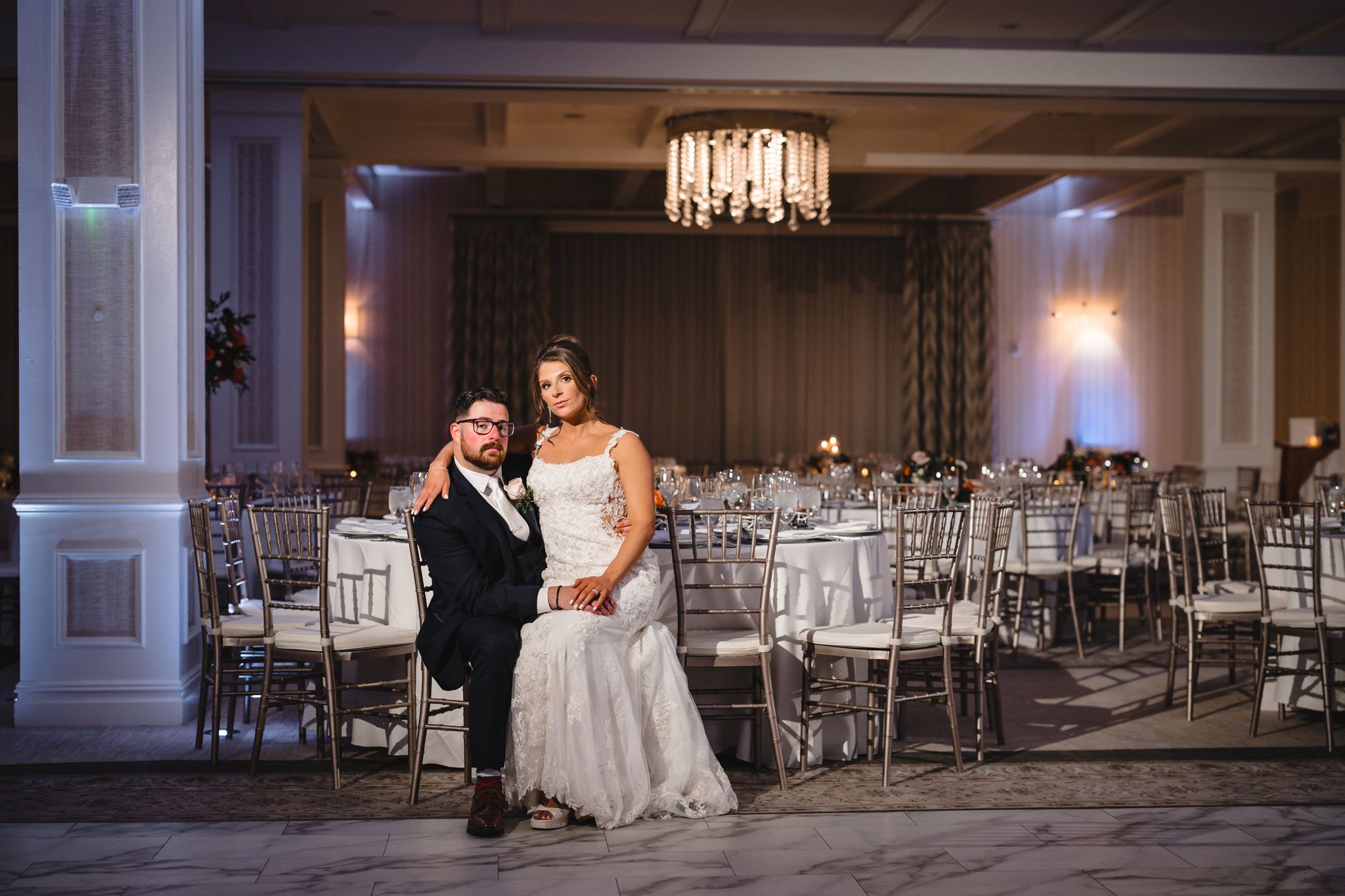 Luxurious wedding reception hall with crystal chandeliers and silver chiavari chairs.