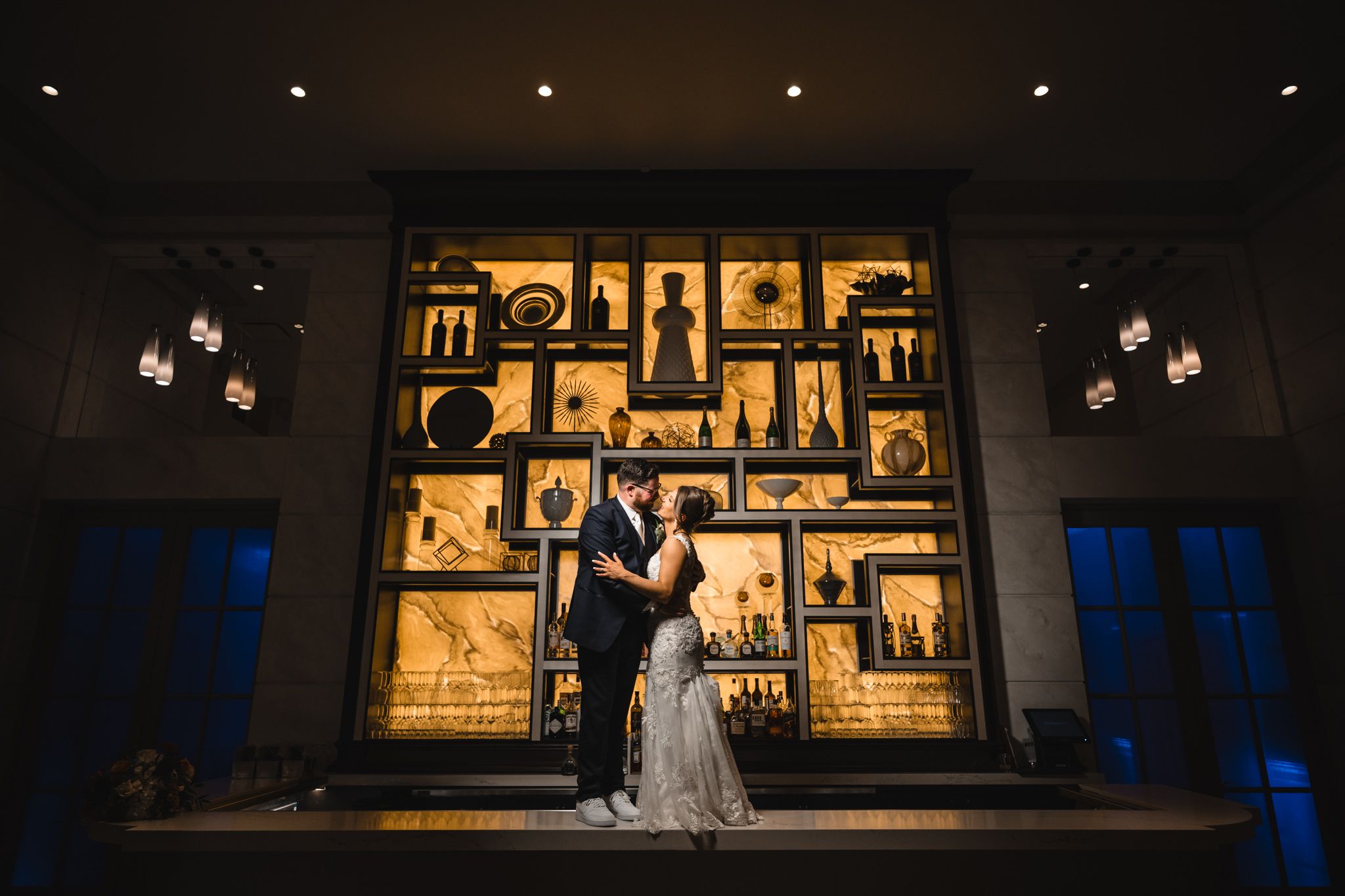 Dramatic nighttime wedding portrait with illuminated decorative wall panels.