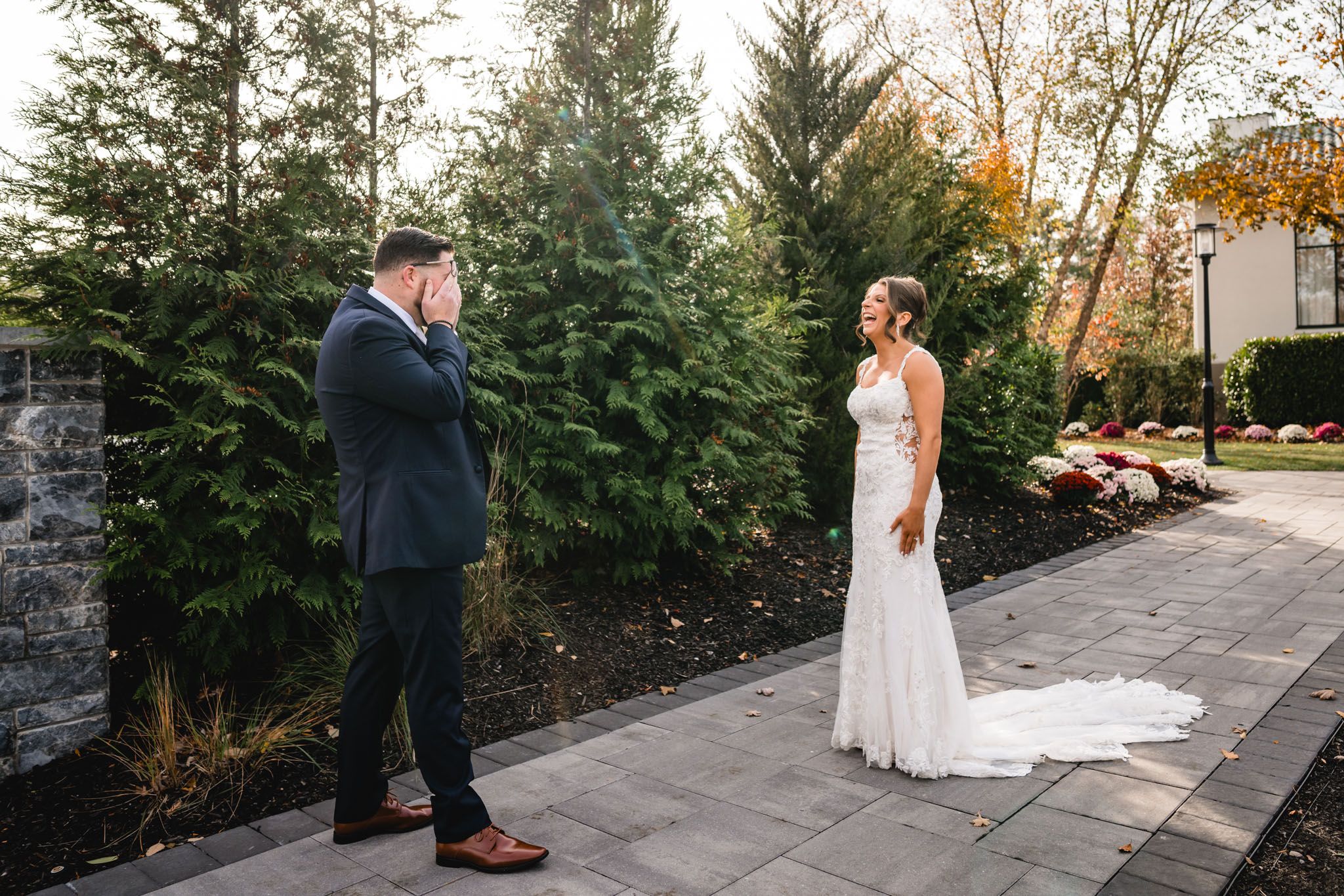 Couple sharing intimate moment on stone pathway with evergreen backdrop.