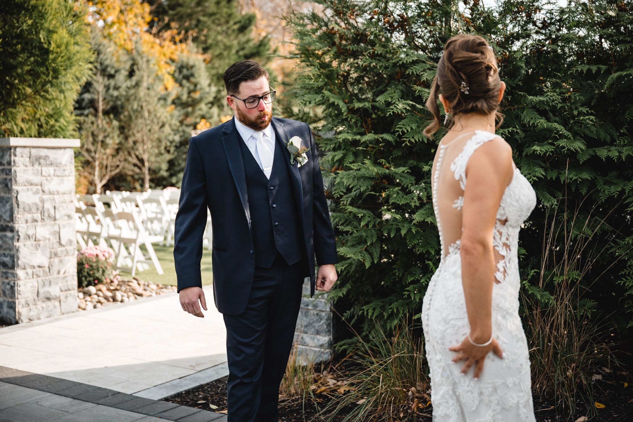 Wedding couple shares an intimate moment against a backdrop of autumn trees and stone walls.
