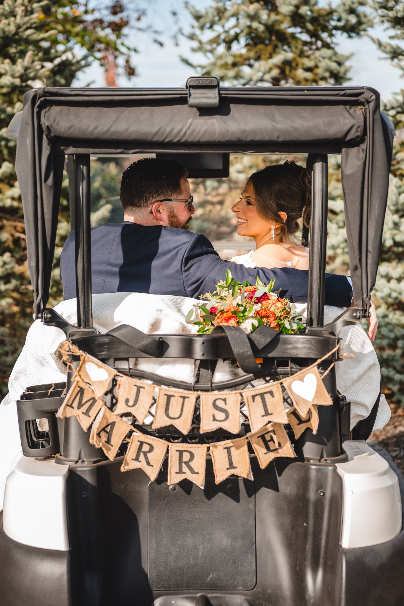 Golf cart decorated with 'Just Married' banner for newlyweds at outdoor wedding.