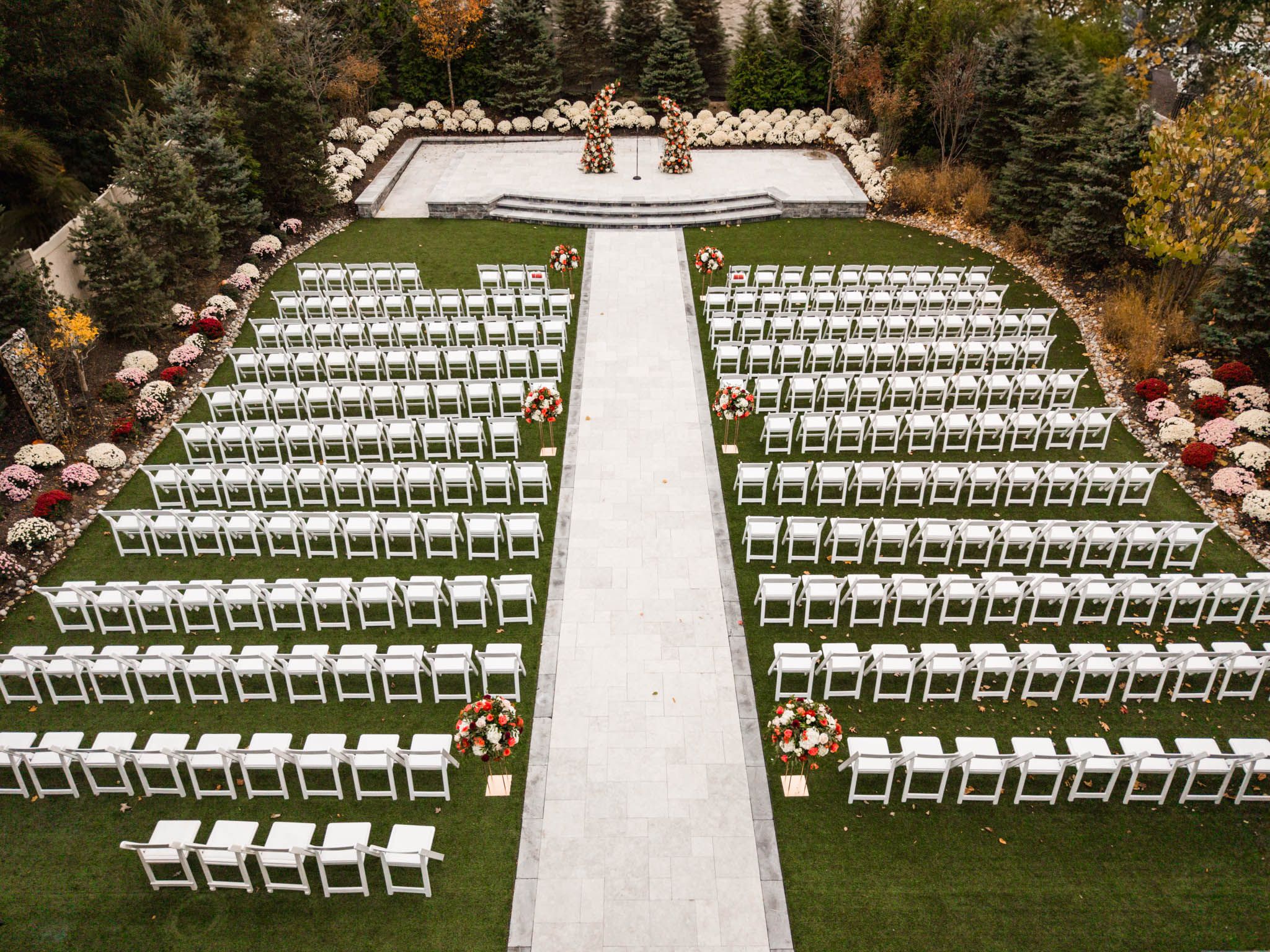 Outdoor wedding ceremony setup with rows of white chairs on a manicured lawn.