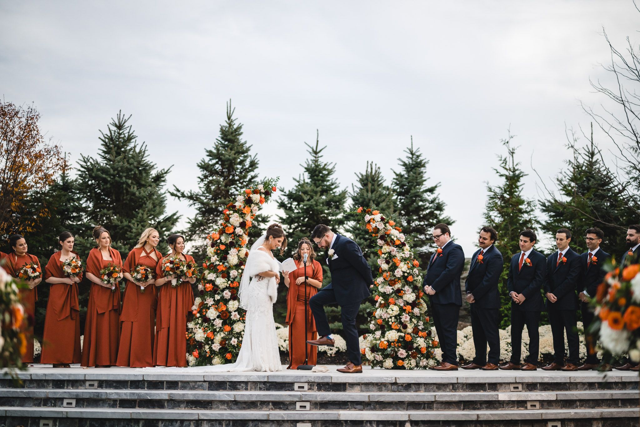 Panoramic view of outdoor wedding ceremony setup with white chairs and floral decorations.