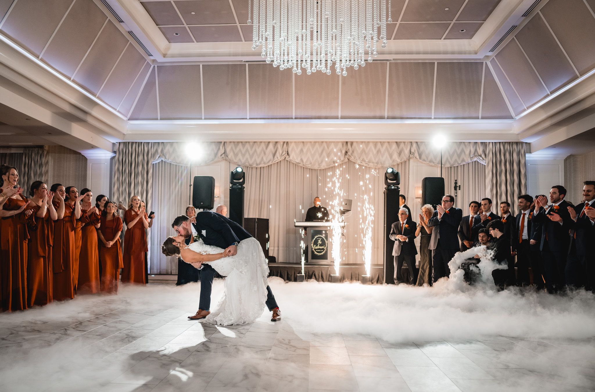 Panoramic view of a wedding reception in an elegant ballroom with dramatic lighting.