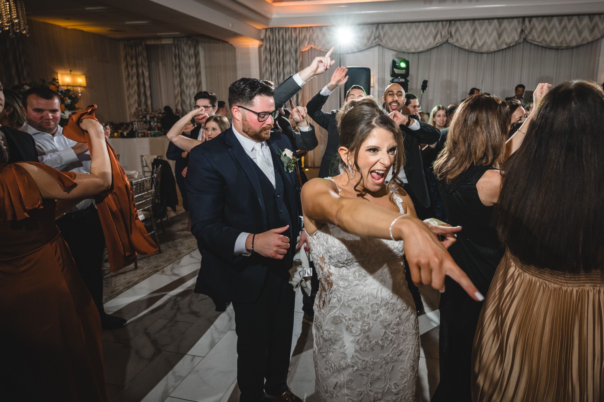 Wedding reception dance floor filled with guests dancing and celebrating in formal attire.