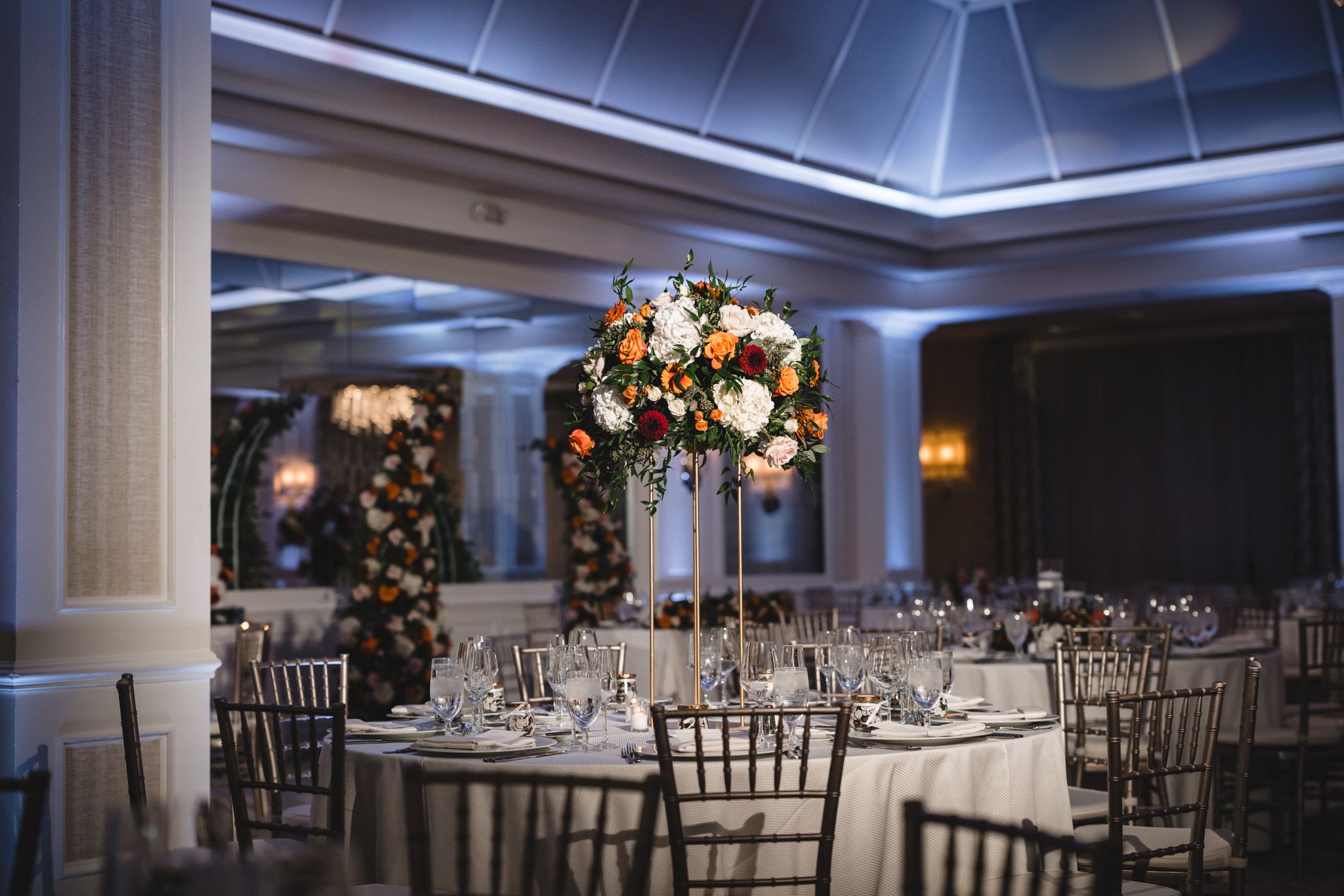 Modern wedding reception venue with dramatic blue ceiling lighting and formal table settings.