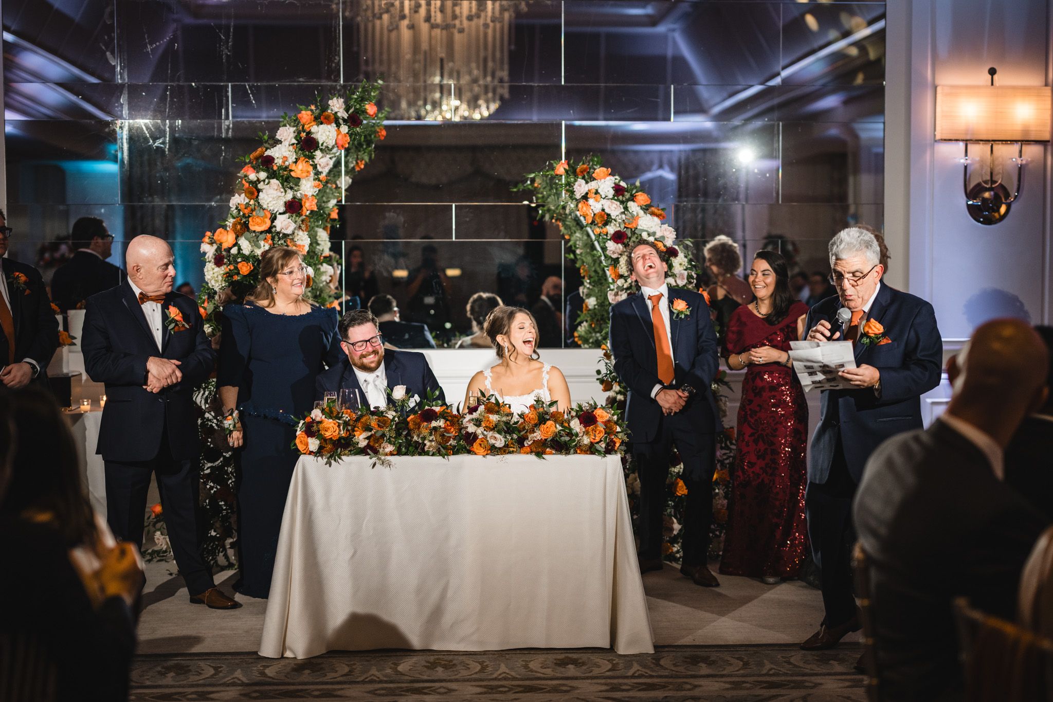 Elegant wedding reception venue with floral centerpieces and chandelier lighting creating romantic ambiance.
