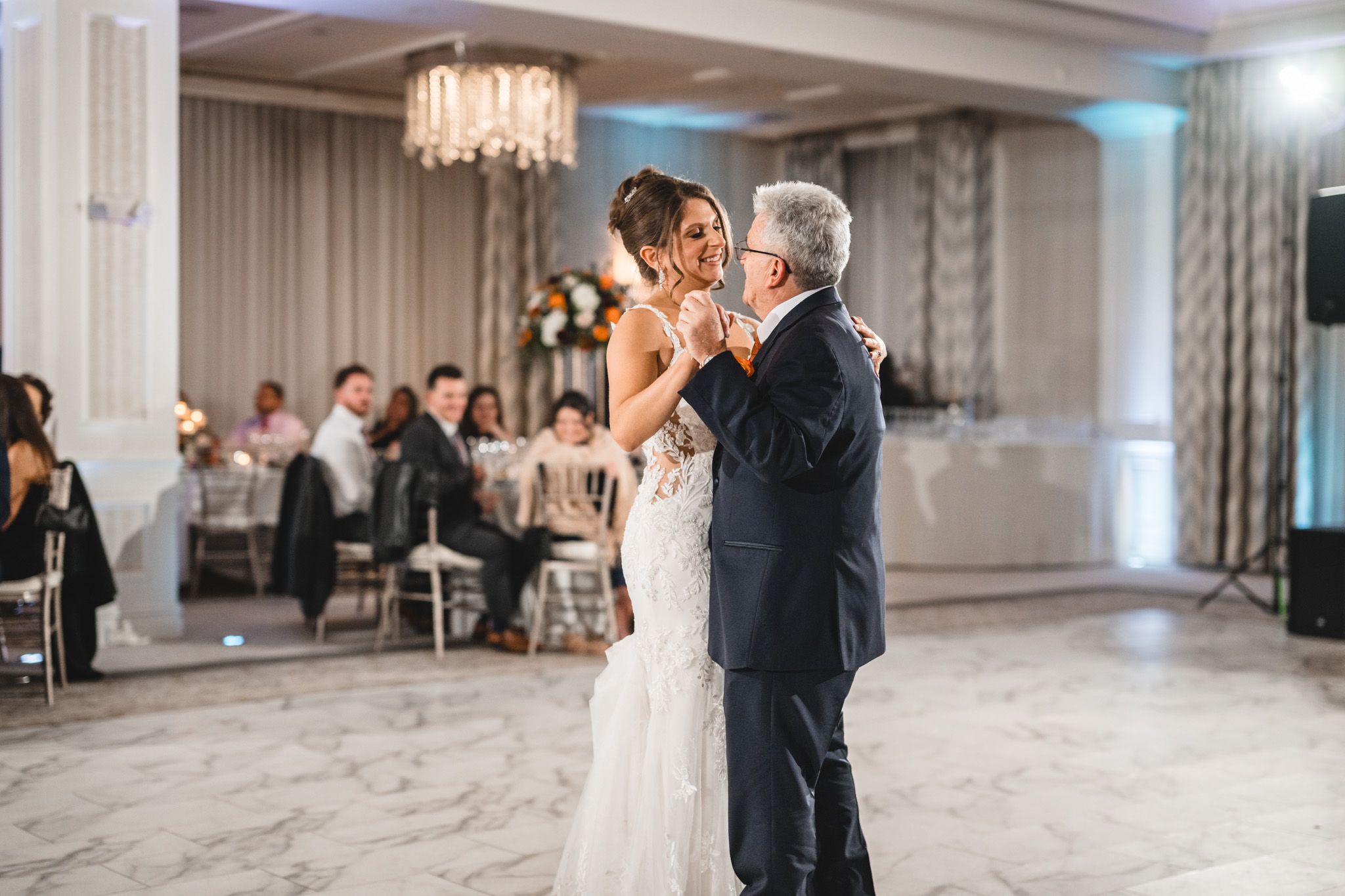 Couple sharing their first dance in an elegant ballroom with soft lighting and classic decor.