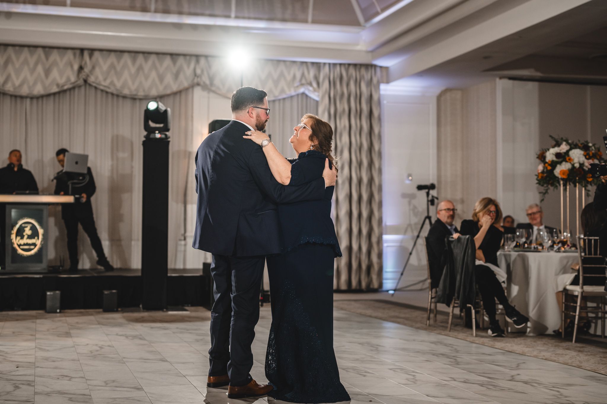 Spacious wedding venue with elegant drapes and modern lighting during an evening celebration.
