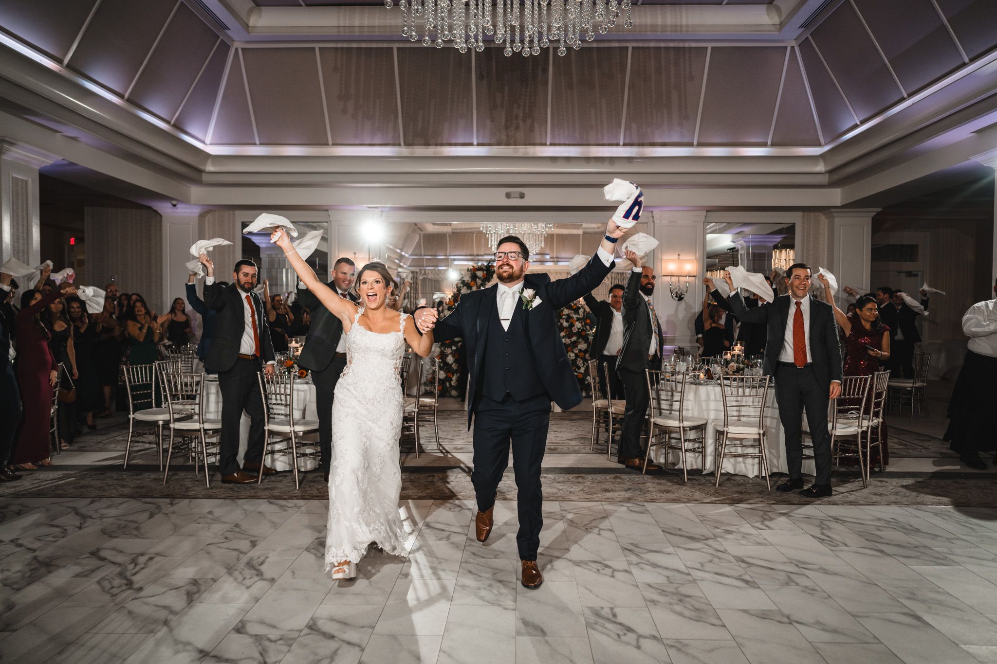 Elegant ballroom with crystal chandelier and marble dance floor during a celebration.