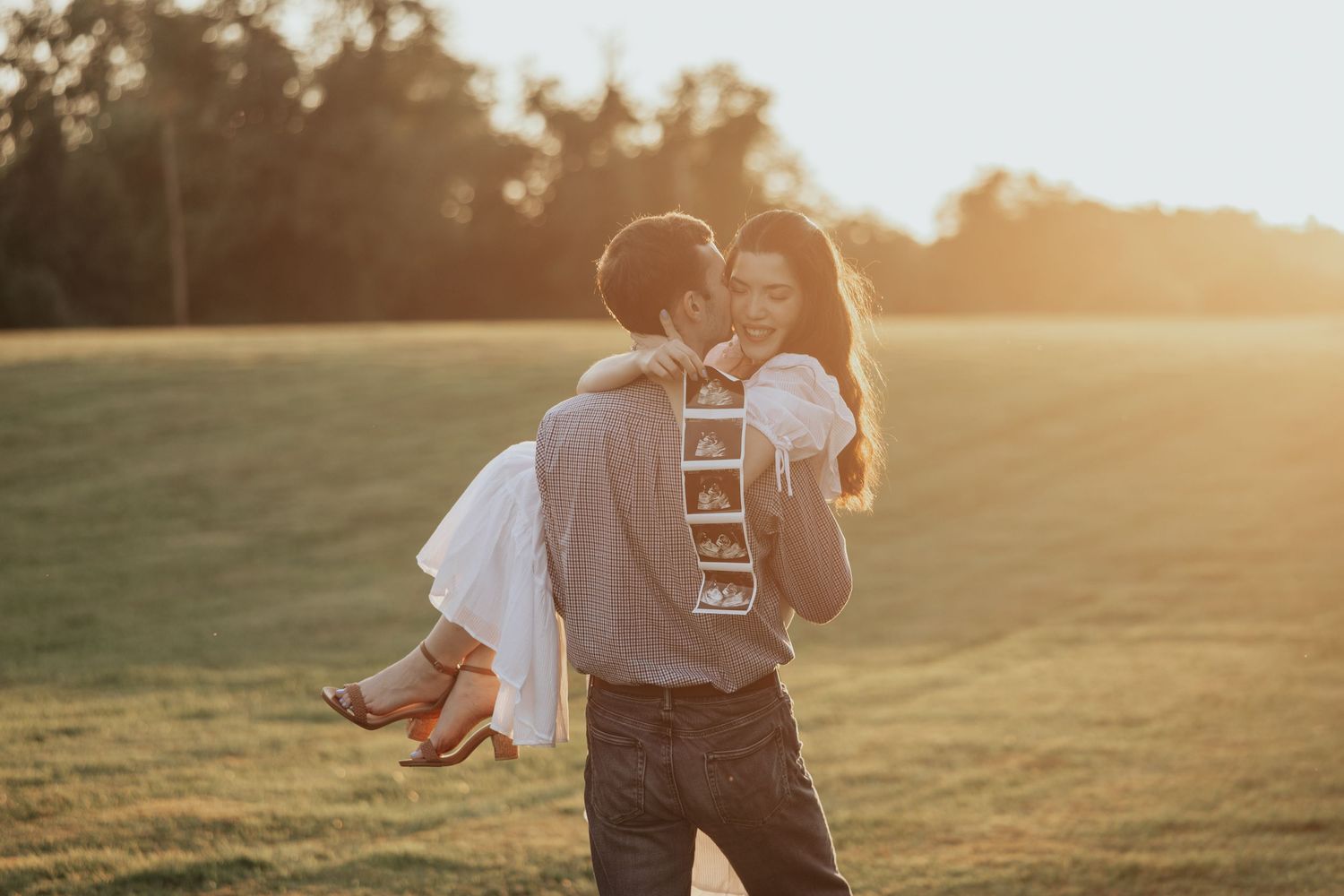 A couple embraces in a sunlit meadow during golden hour, creating a romantic silhouette against the warm sky.