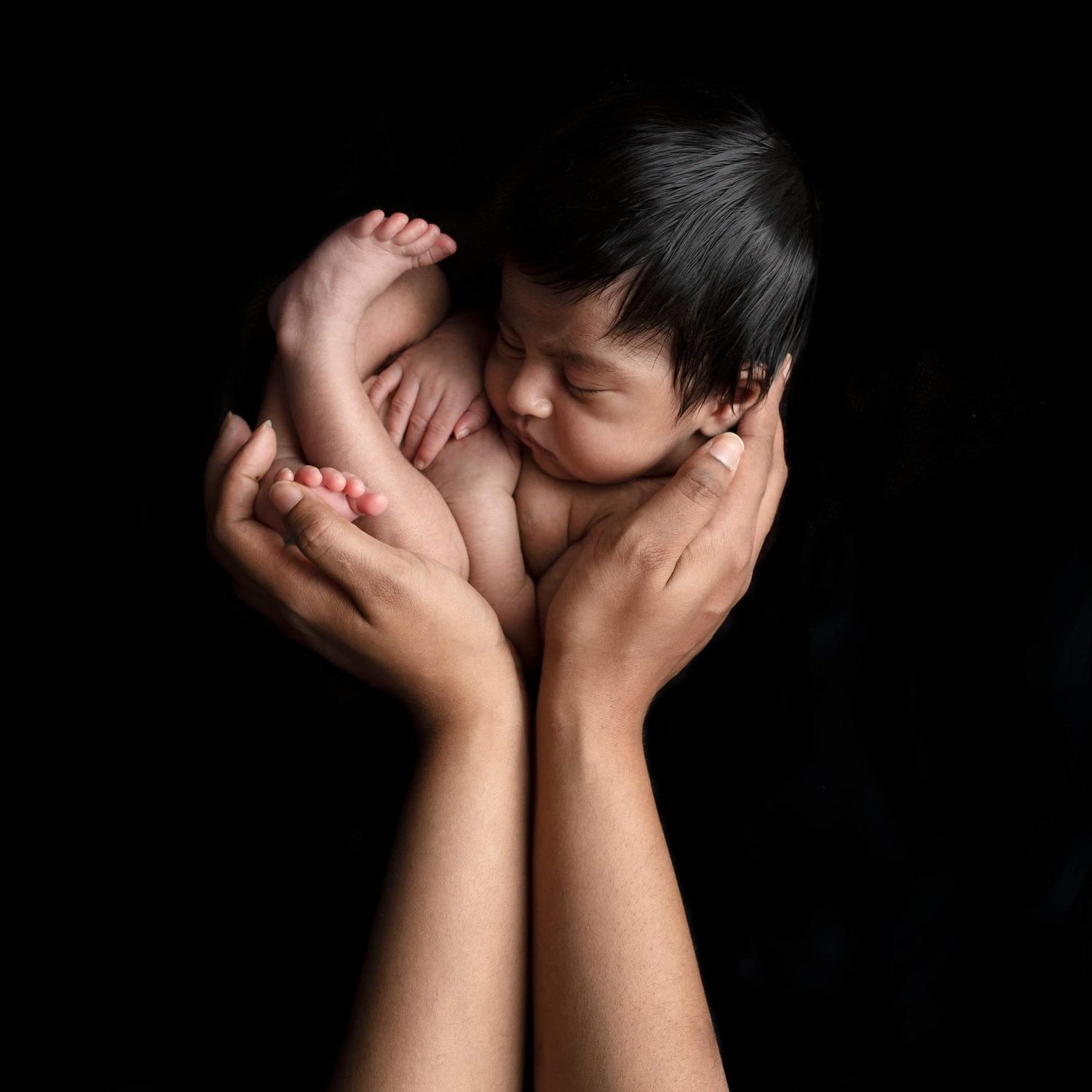 Hands covering face against dark background in dramatic artistic portrait series showing vulnerability and emotion.