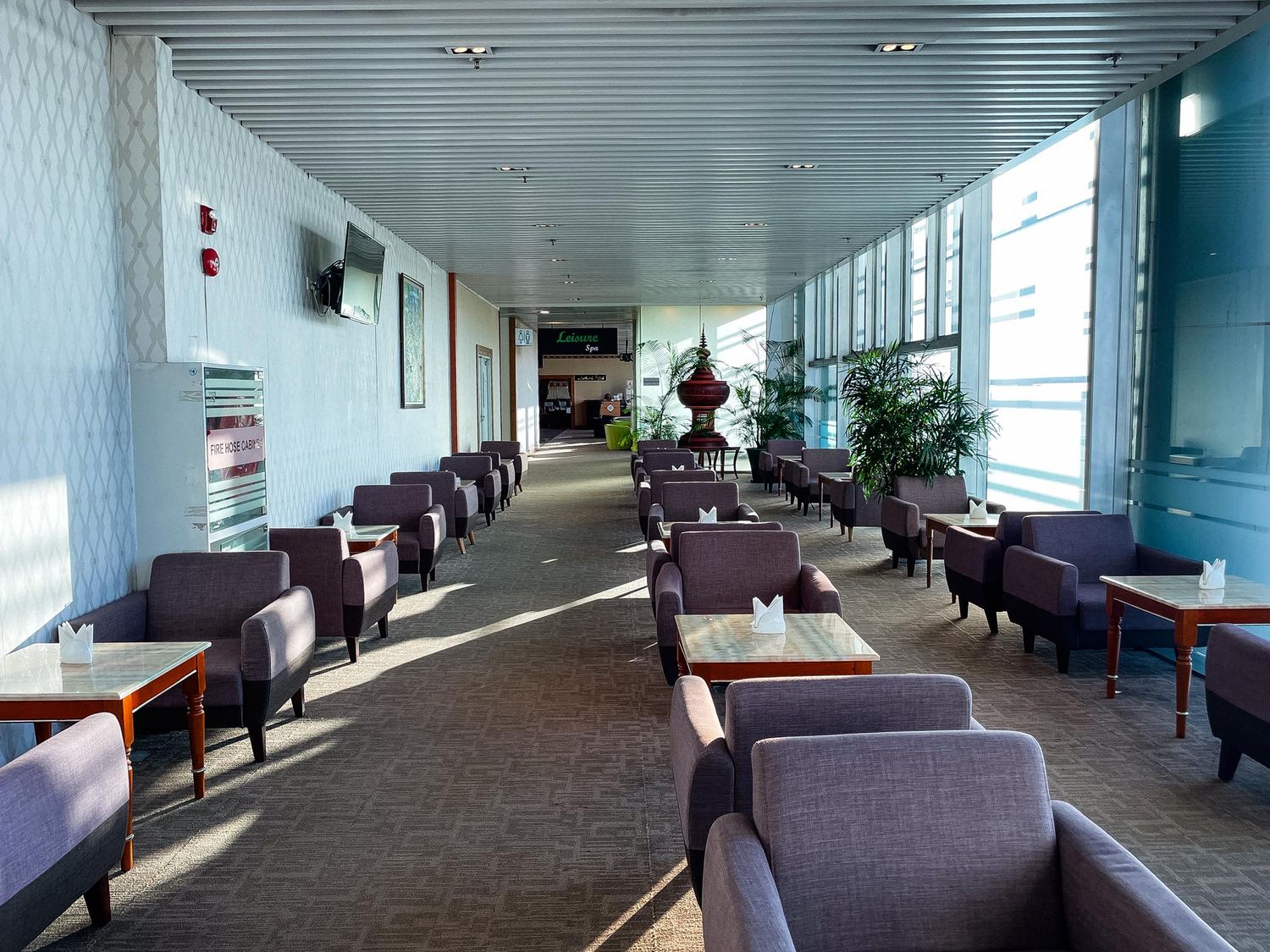 Long hallway with plush purple chairs and tables arranged along windows in a modern office or study space.
