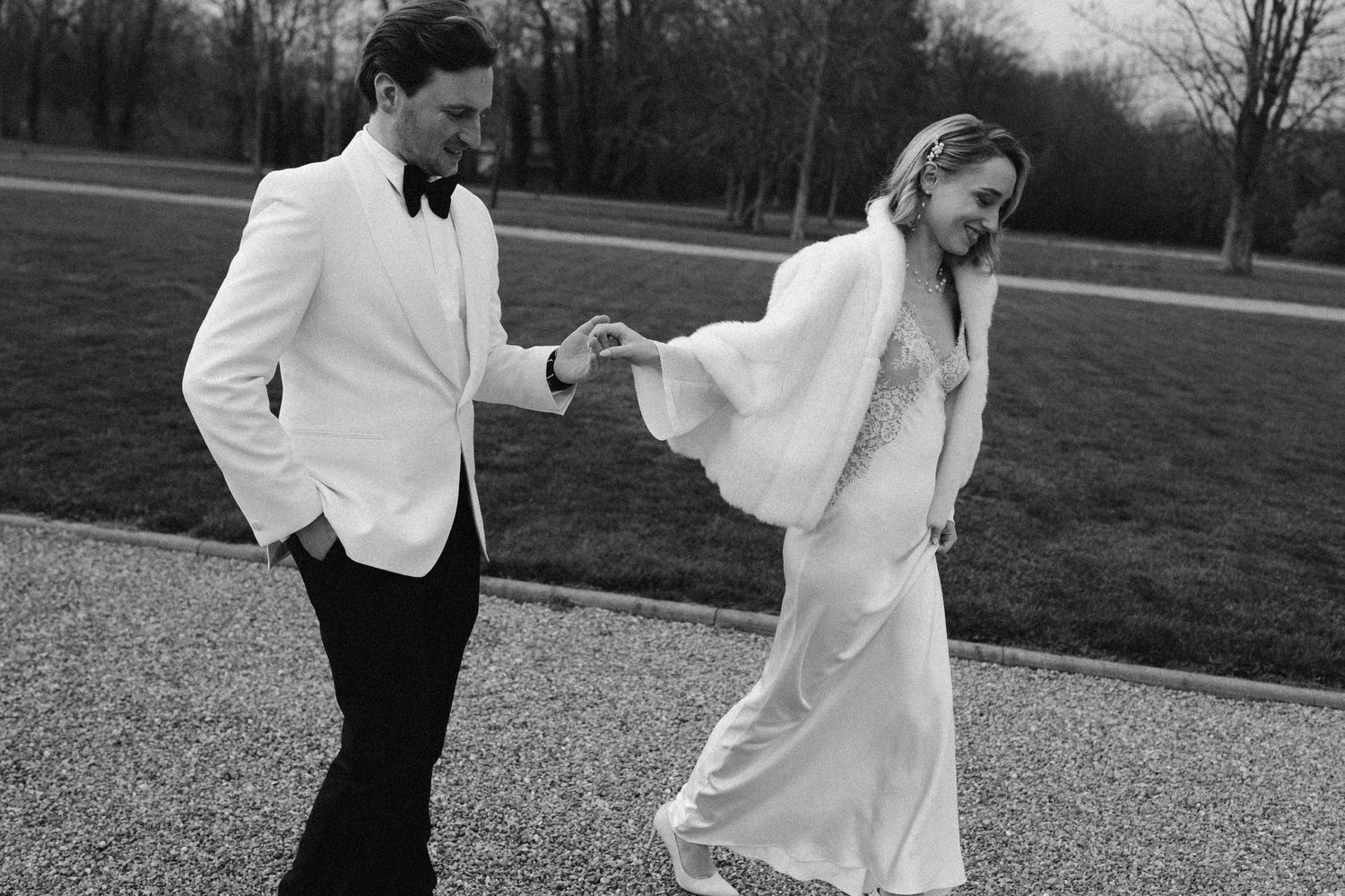 A romantic black and white wedding photograph showing a tender embrace in a natural outdoor setting.
