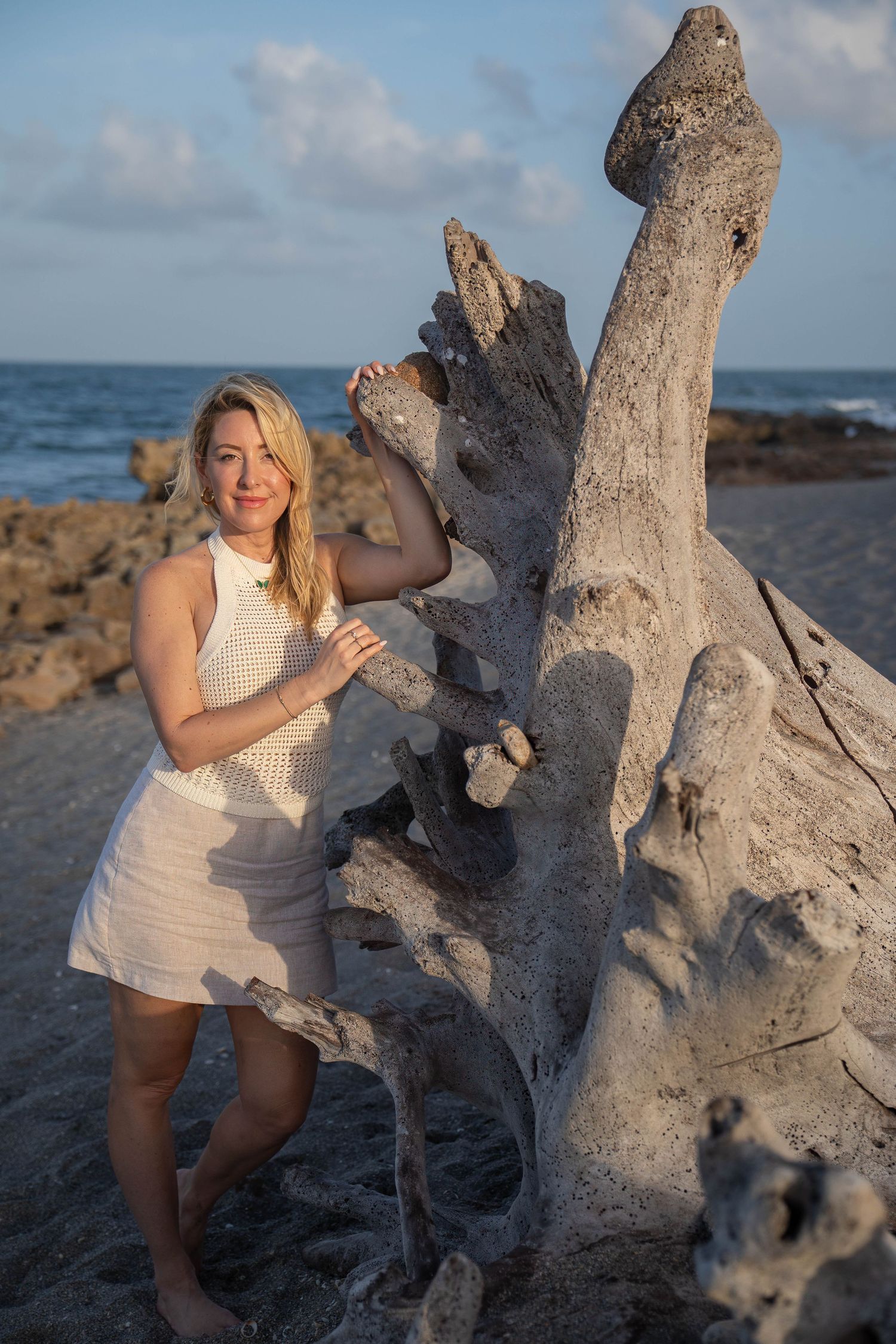 Client on the sand, next to a driftwood of coral cove beach, tequesta florida, during an individual photo shoot