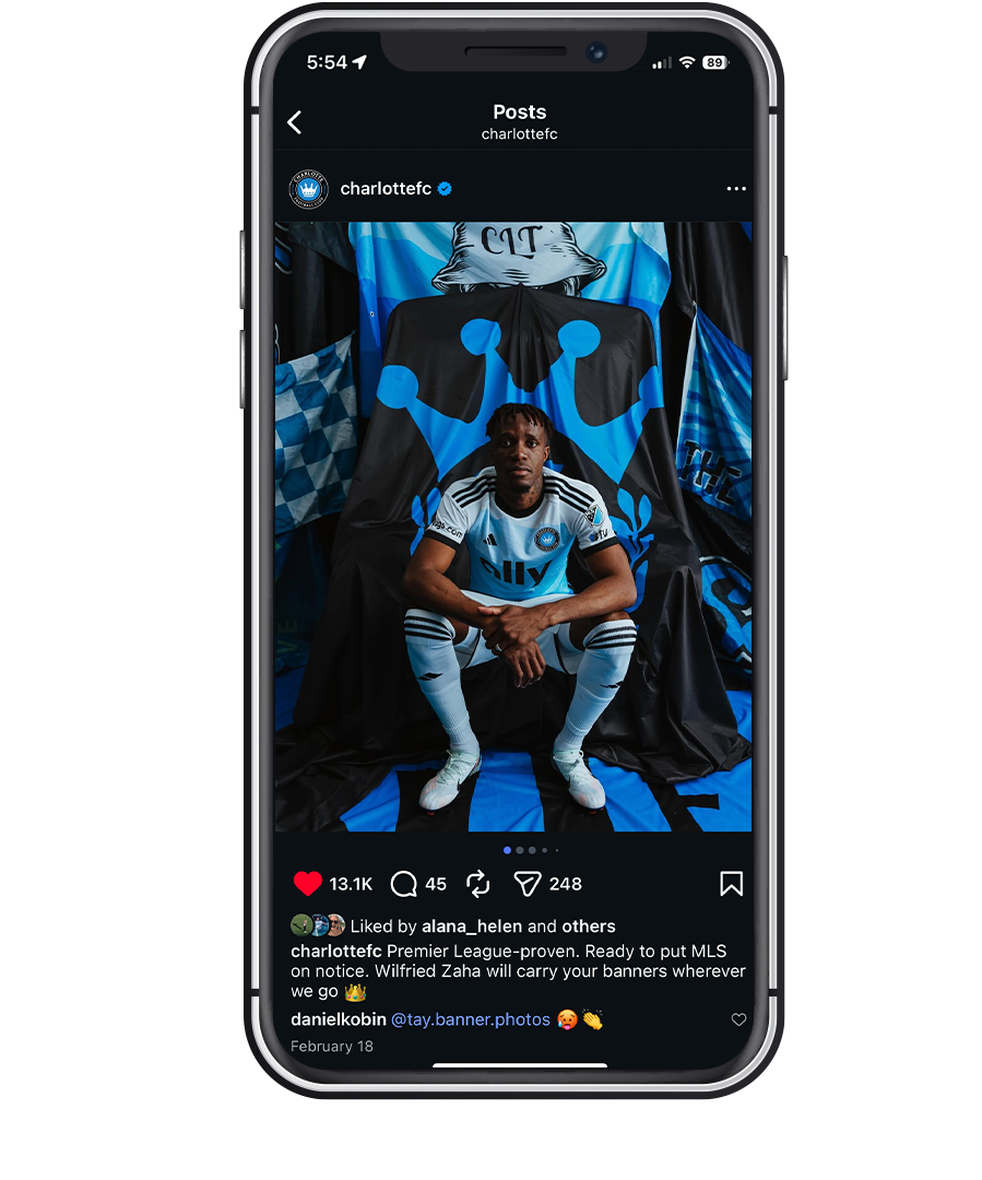 Wilfried Zaha poses with Charlotte FC banner flags on Instagram post with 13.1K likes.