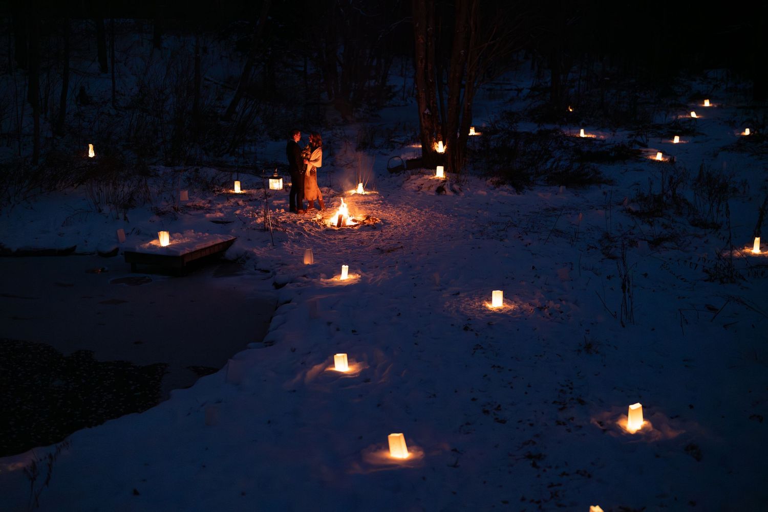 Paper lanterns cast a warm glow along a snowy winter walkway.