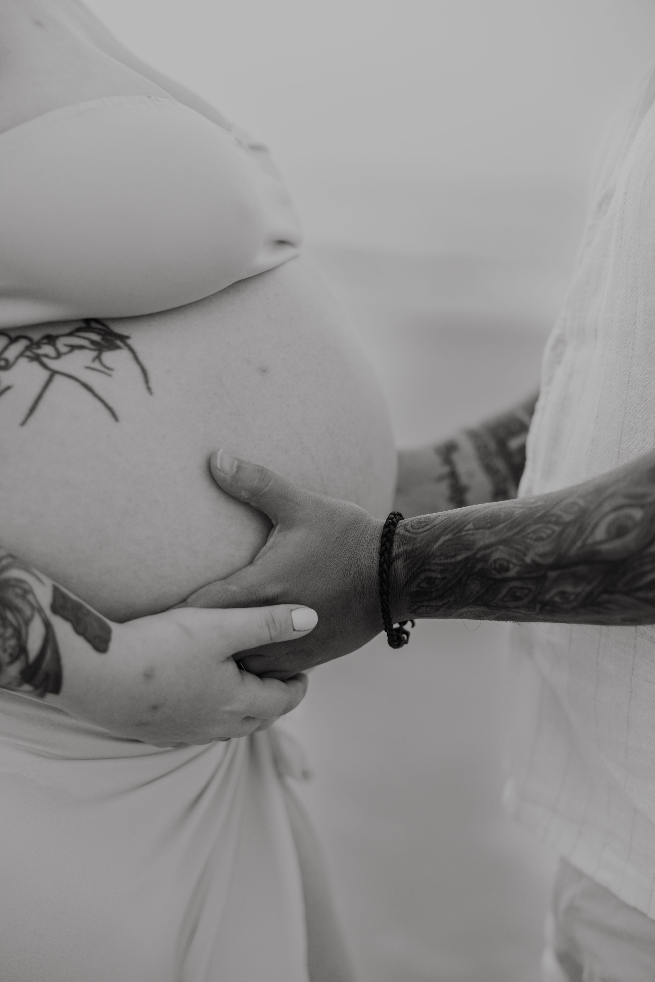 Black and white detail shots of hands with tattoos and tender gestures.