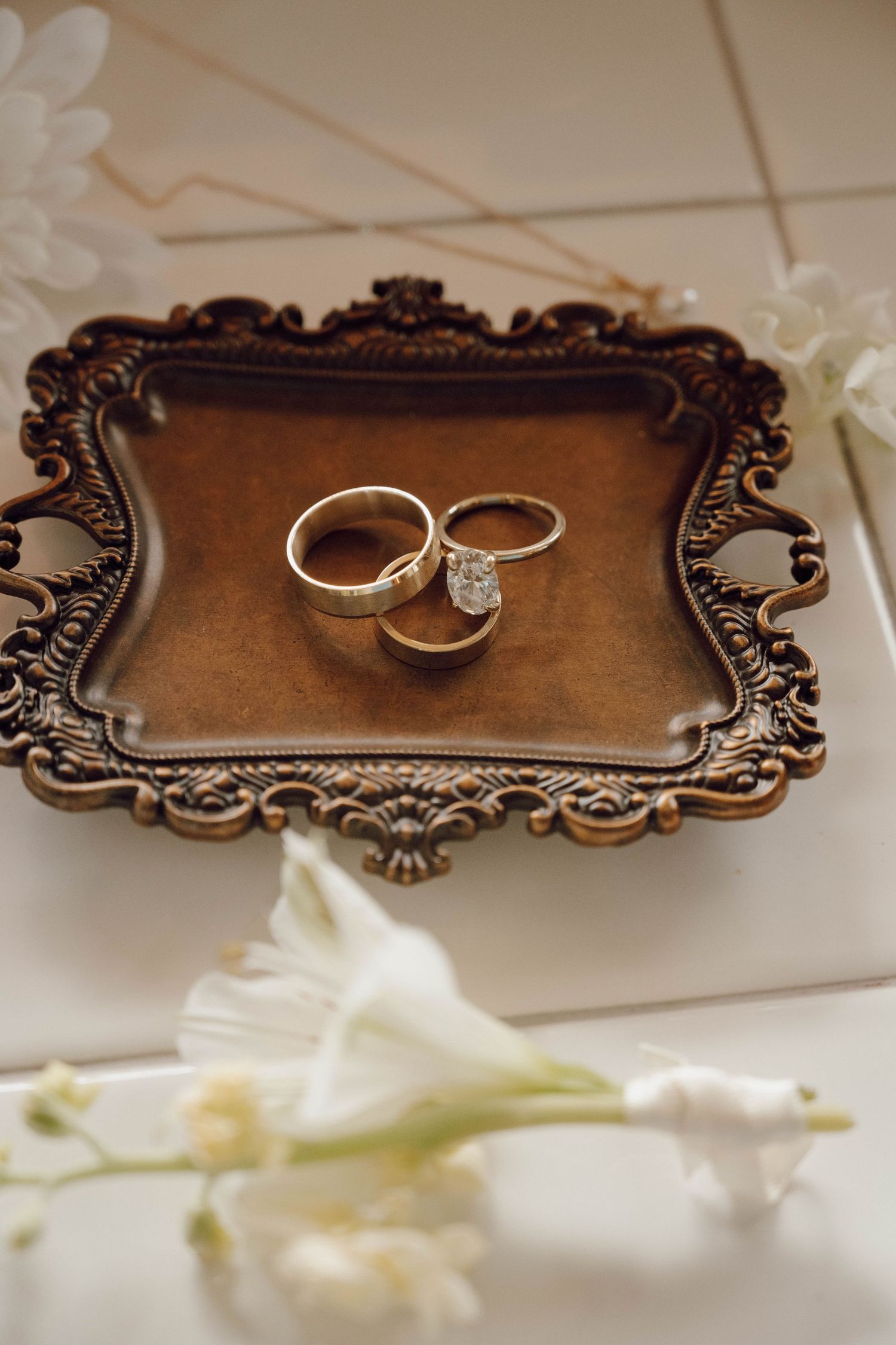 Wedding rings displayed on an ornate vintage bronze tray with decorative edges.