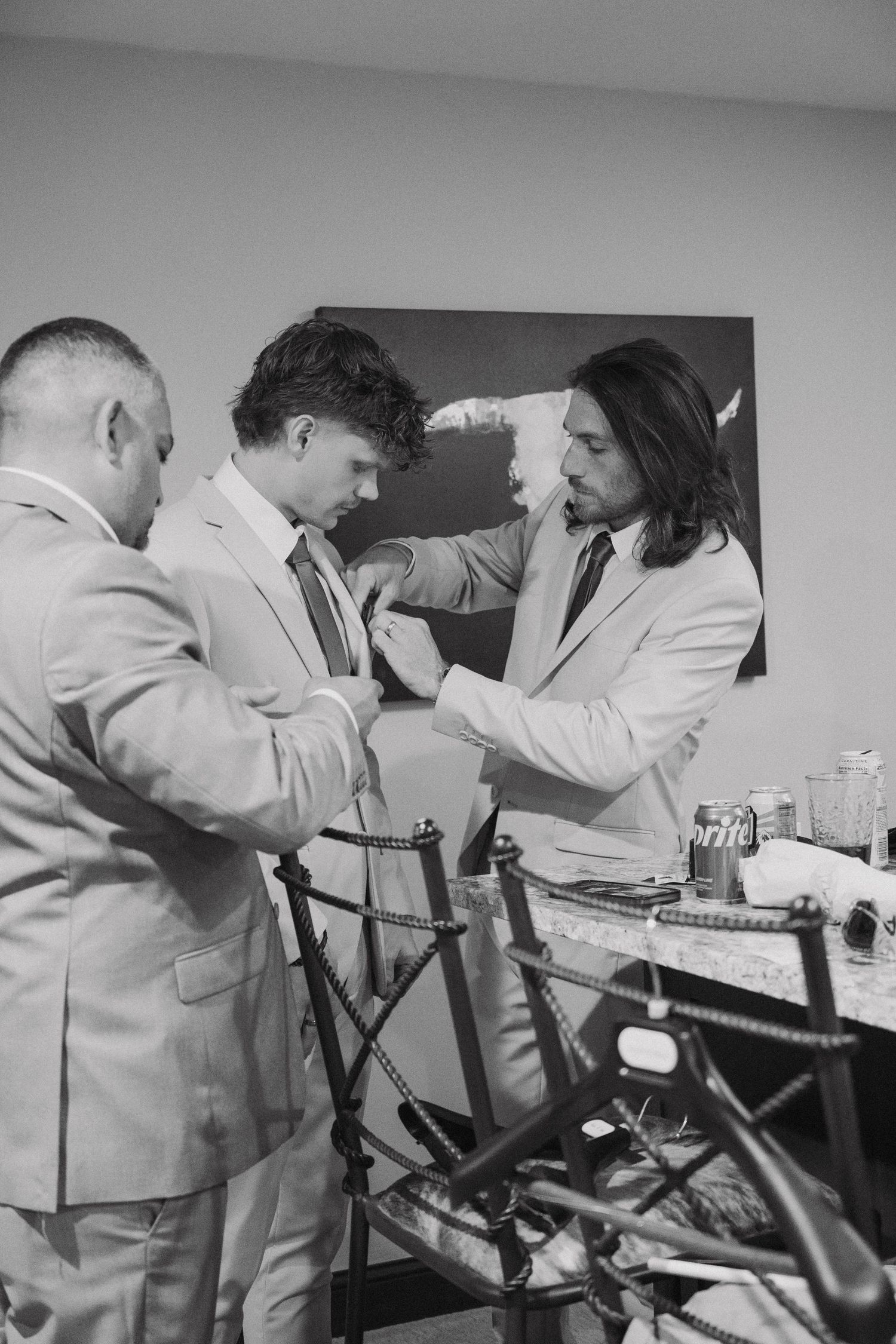 Groomsmen getting ready in black and white photo showing preparation before wedding ceremony.