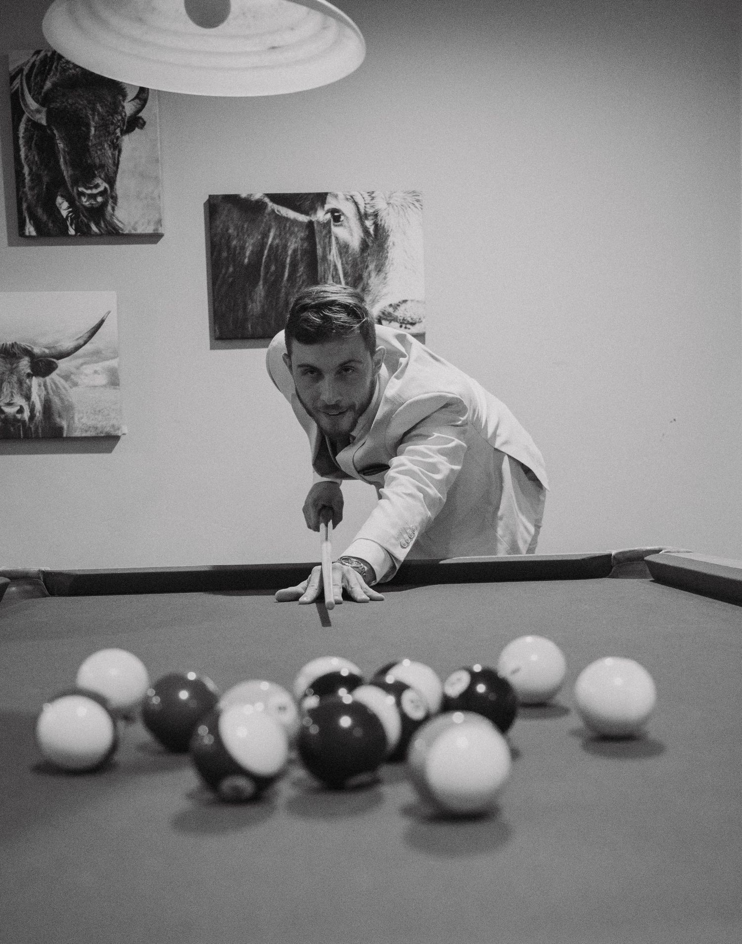 Black and white photo of someone lining up a shot on a pool table.